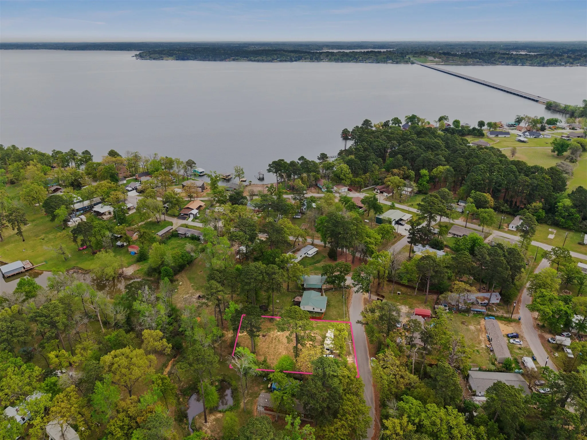 Aerial view of a wooded property with a pond, bordered by a road