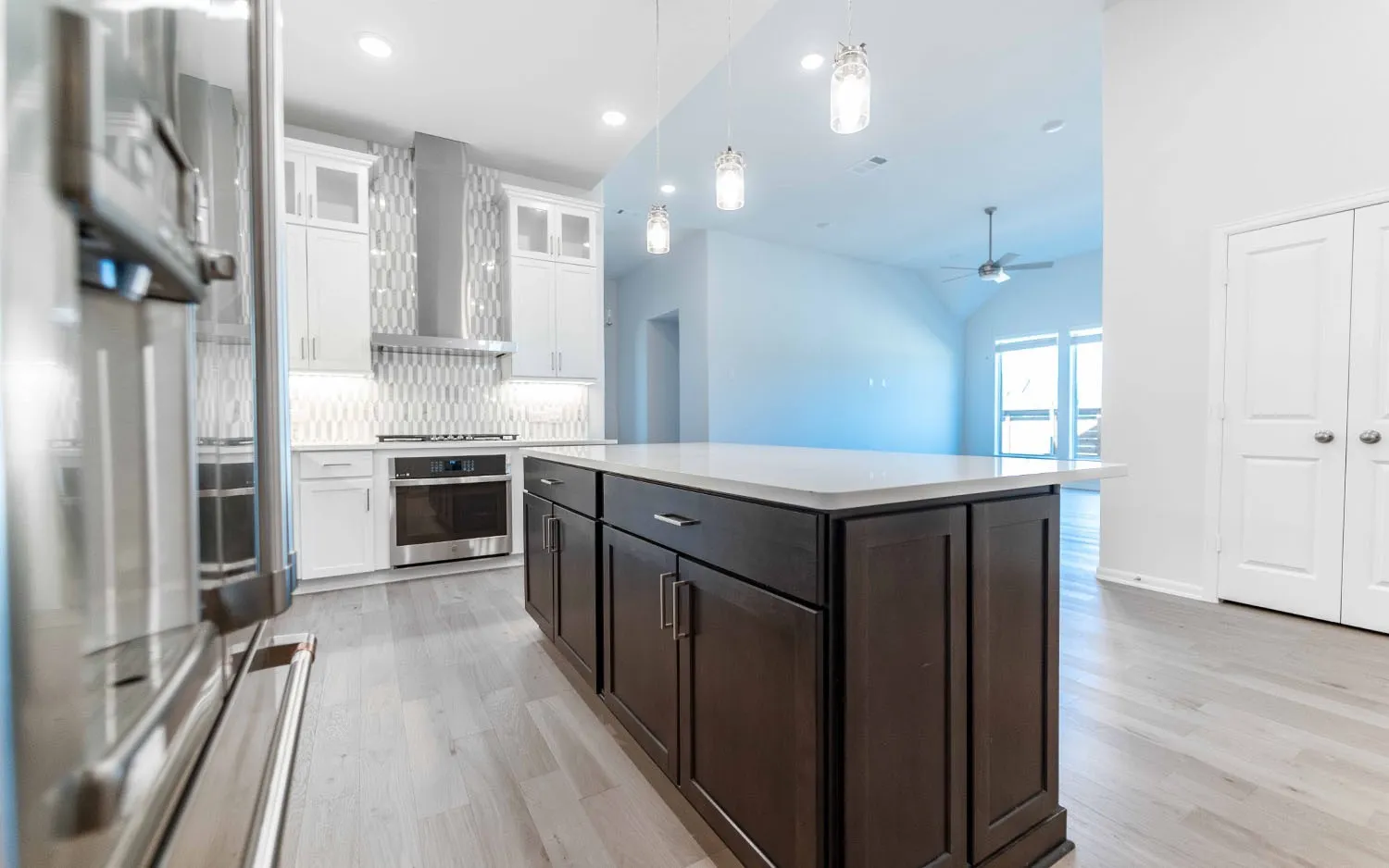 Spacious kitchen island with a light-toned countertop, dark wood-finish cabinetry, and three pendant lights