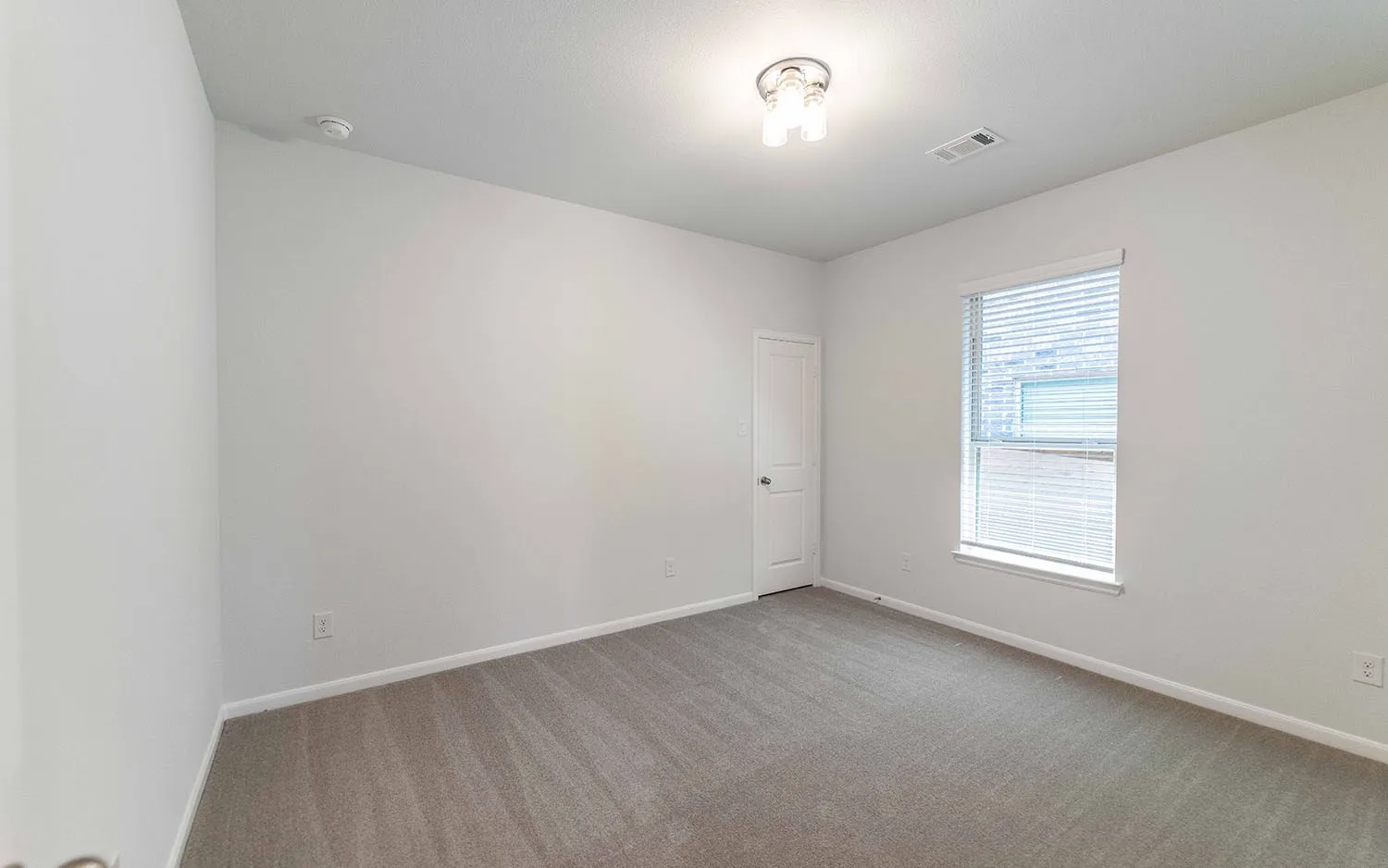 Room featuring light gray carpeting, neutral-toned walls, and a window with blinds