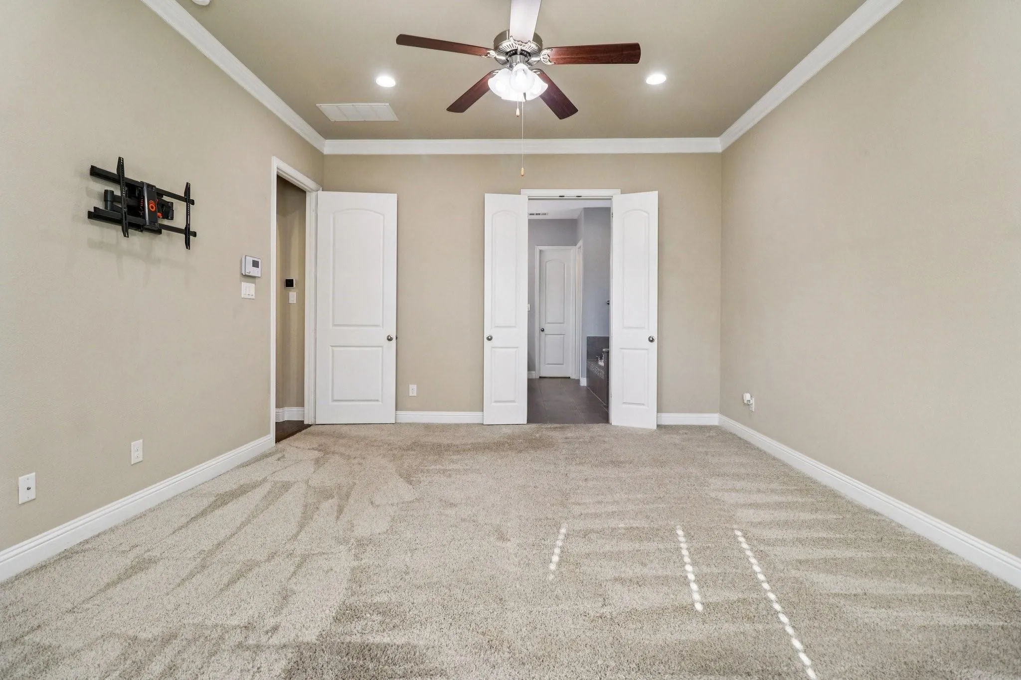 Spacious room featuring neutral carpeting, crown molding, a ceiling fan, recessed lighting, and white paneled doors