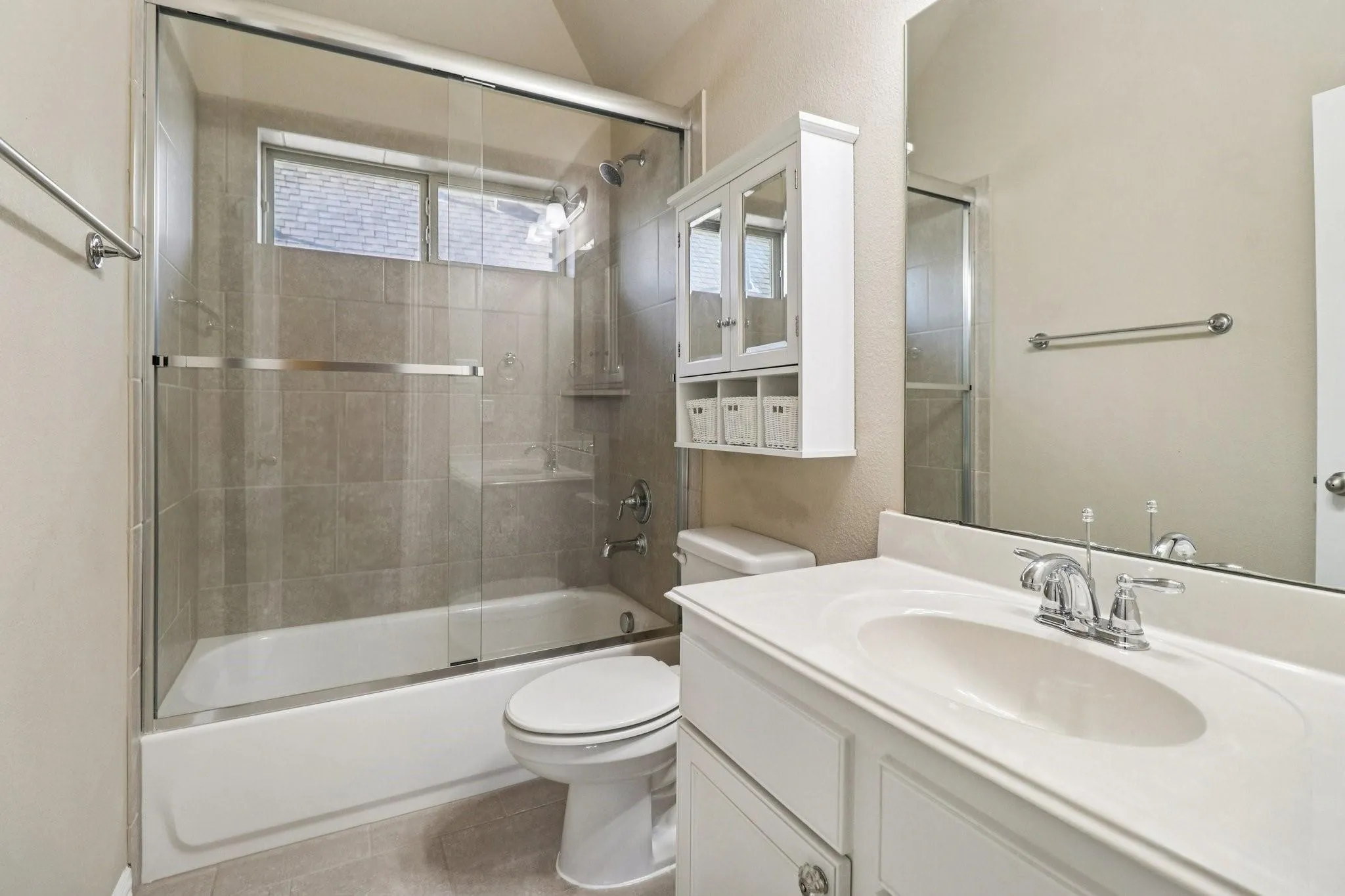Bathroom featuring a tub/shower combination with glass enclosure and tile surround
