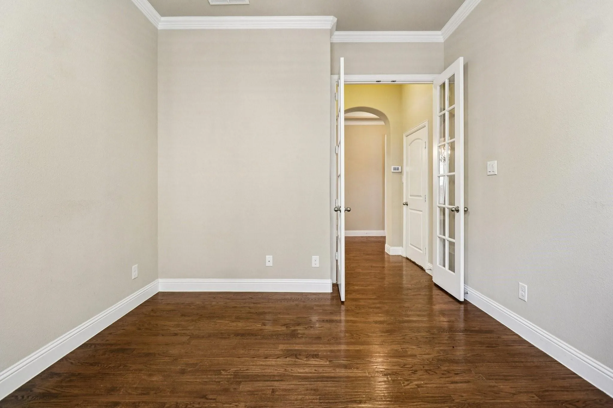 Interior space featuring wood-finish flooring, light neutral wall paint, and white crown molding