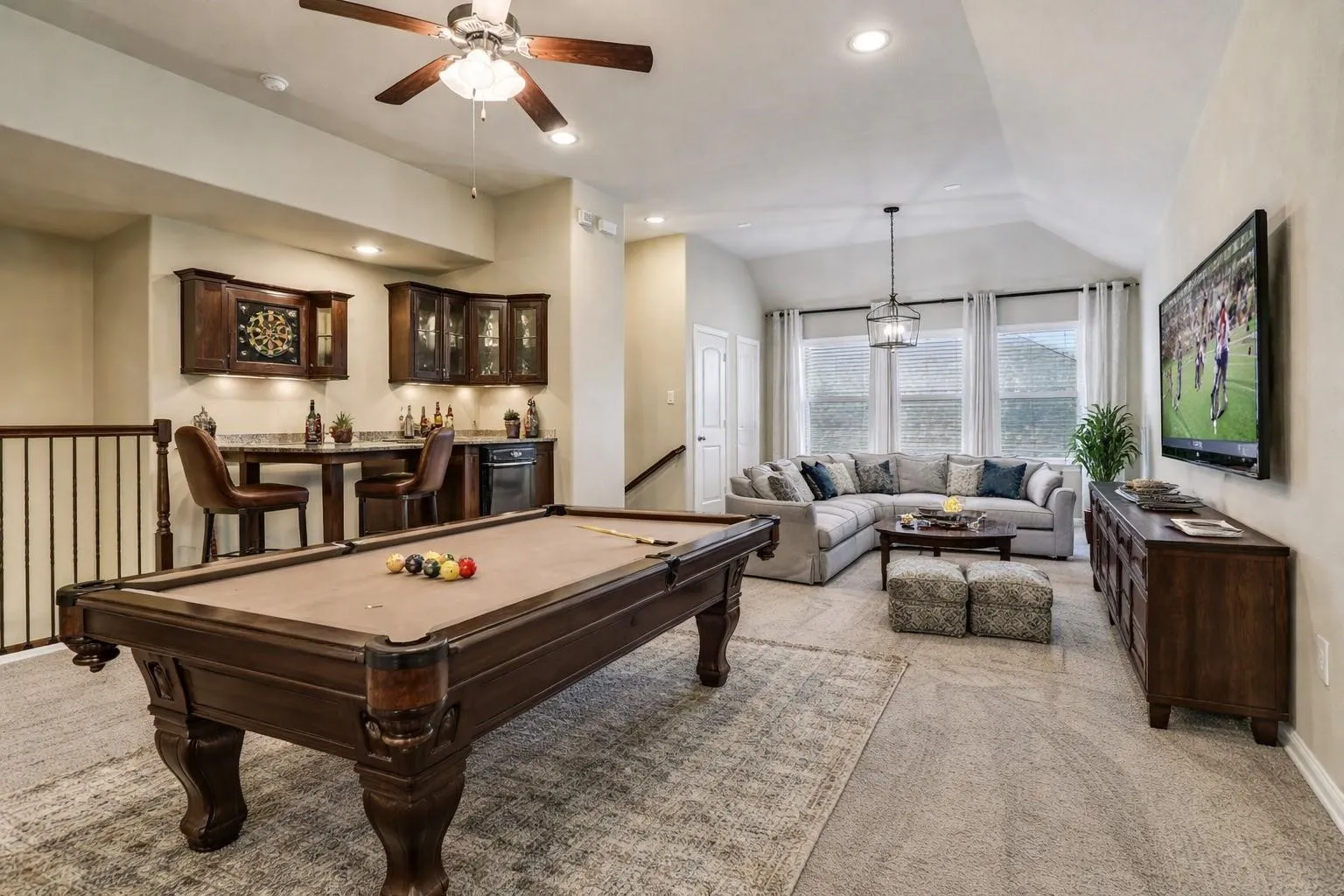Virtual image. Entertainment space featuring a built-in wet bar with wood cabinetry and stone-finish countertop, recessed lighting, and a vaulted ceiling