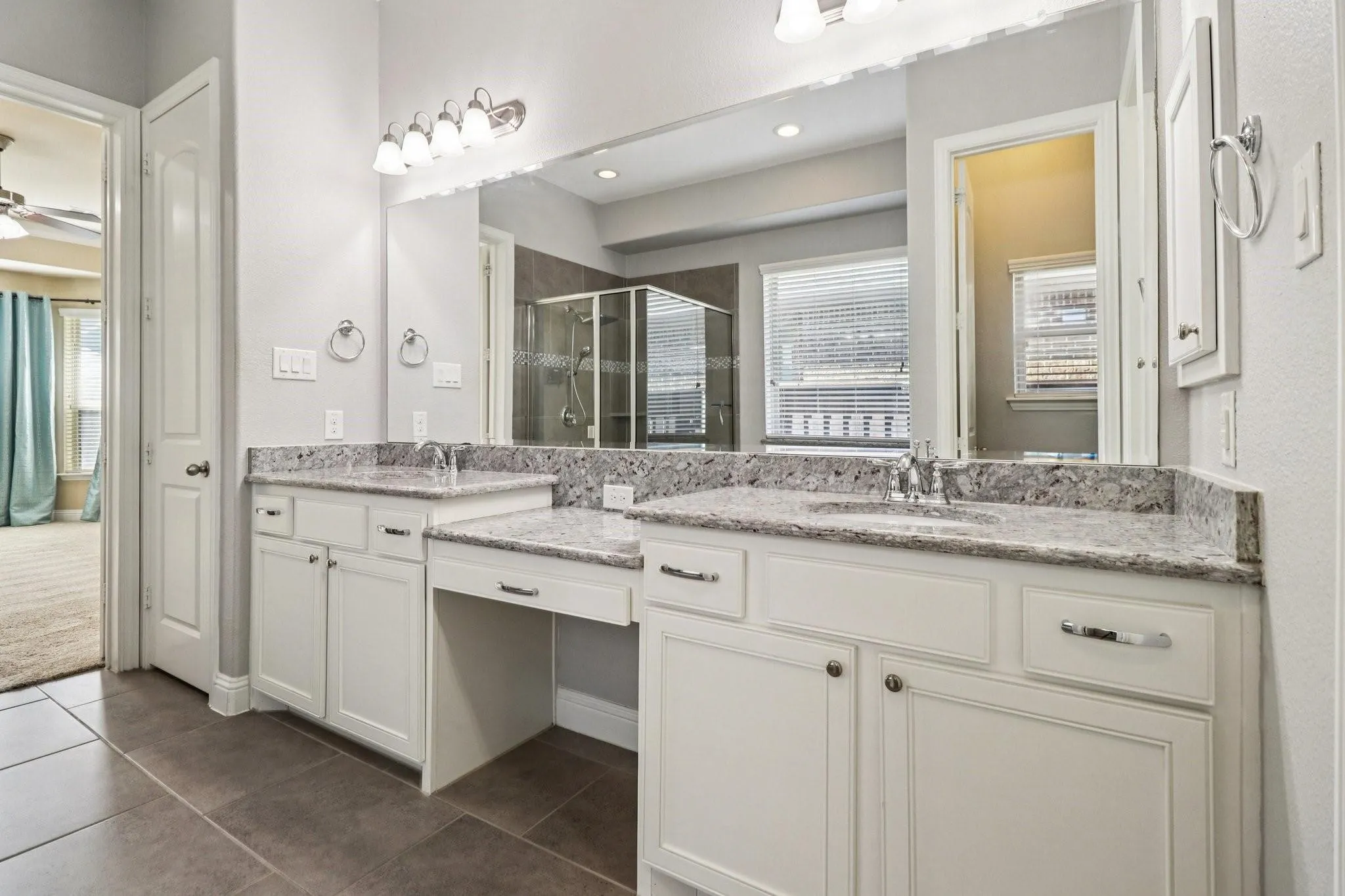 Dual vanity with granite countertops, undermount sinks, and white cabinetry