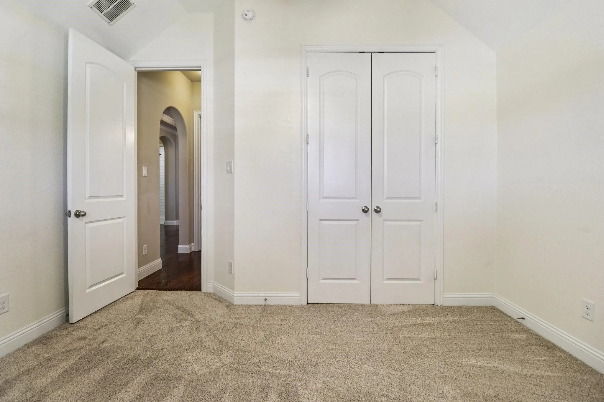 Carpeted room featuring a double-door closet, vaulted ceiling, and white trim