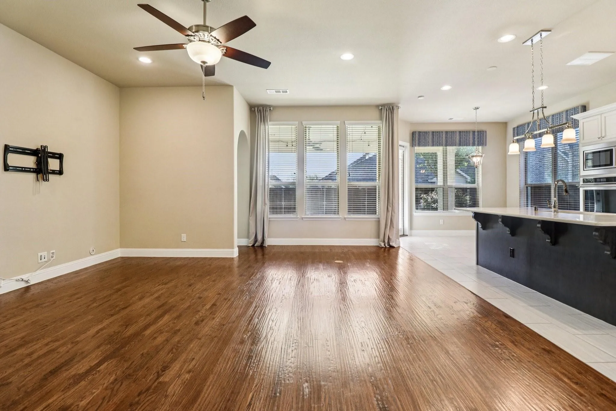 Open-concept living area featuring rich wood-finish flooring, recessed lighting, and a ceiling fan with integrated light