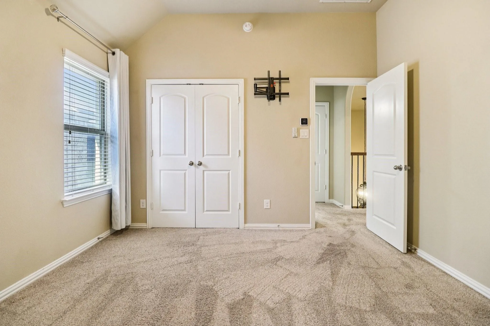 Room featuring neutral-toned carpeting, a vaulted ceiling, and beige wall paint