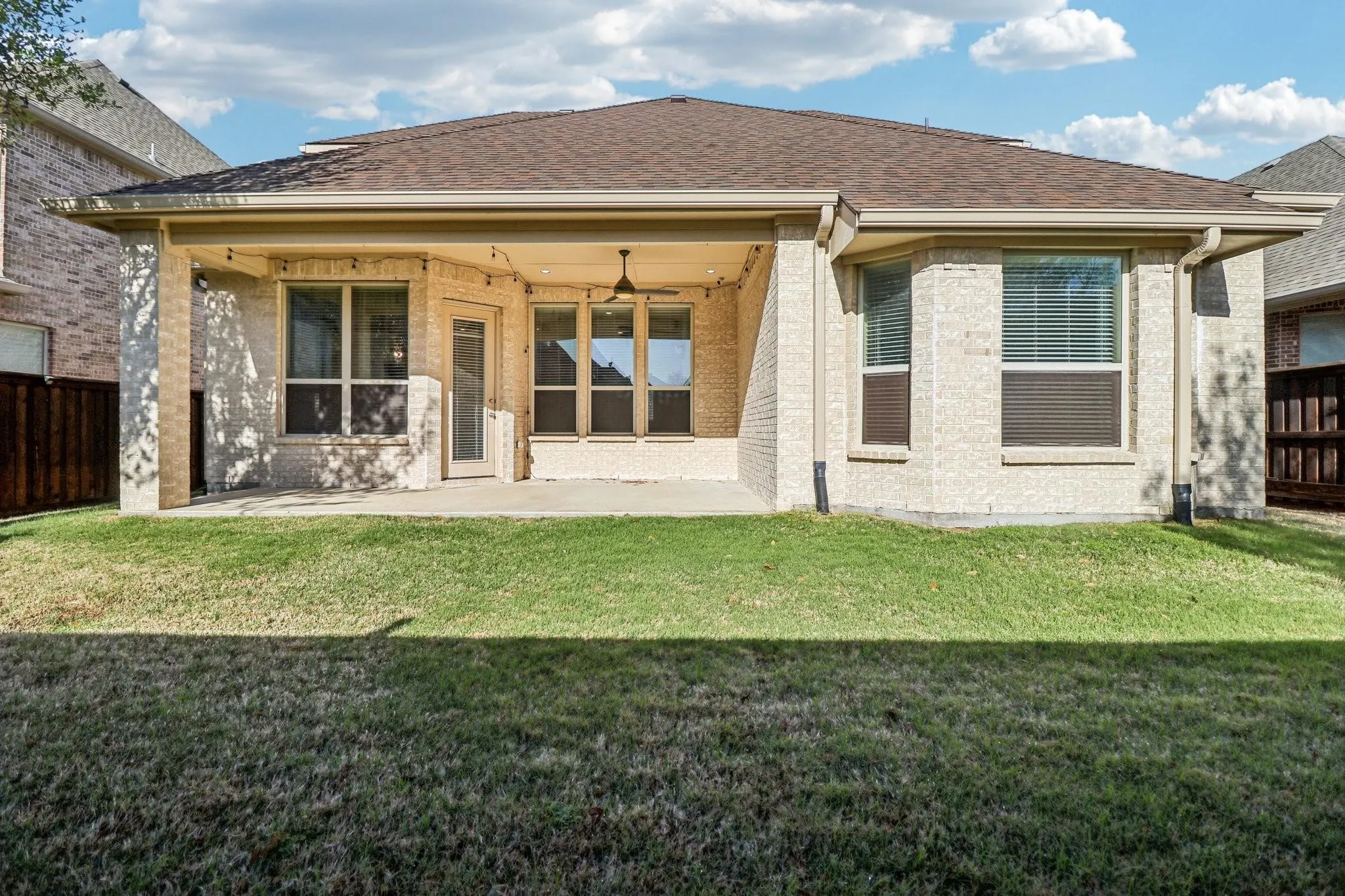 Expansive backyard featuring a covered patio, ceiling fan, string lighting, and direct access to interior spaces