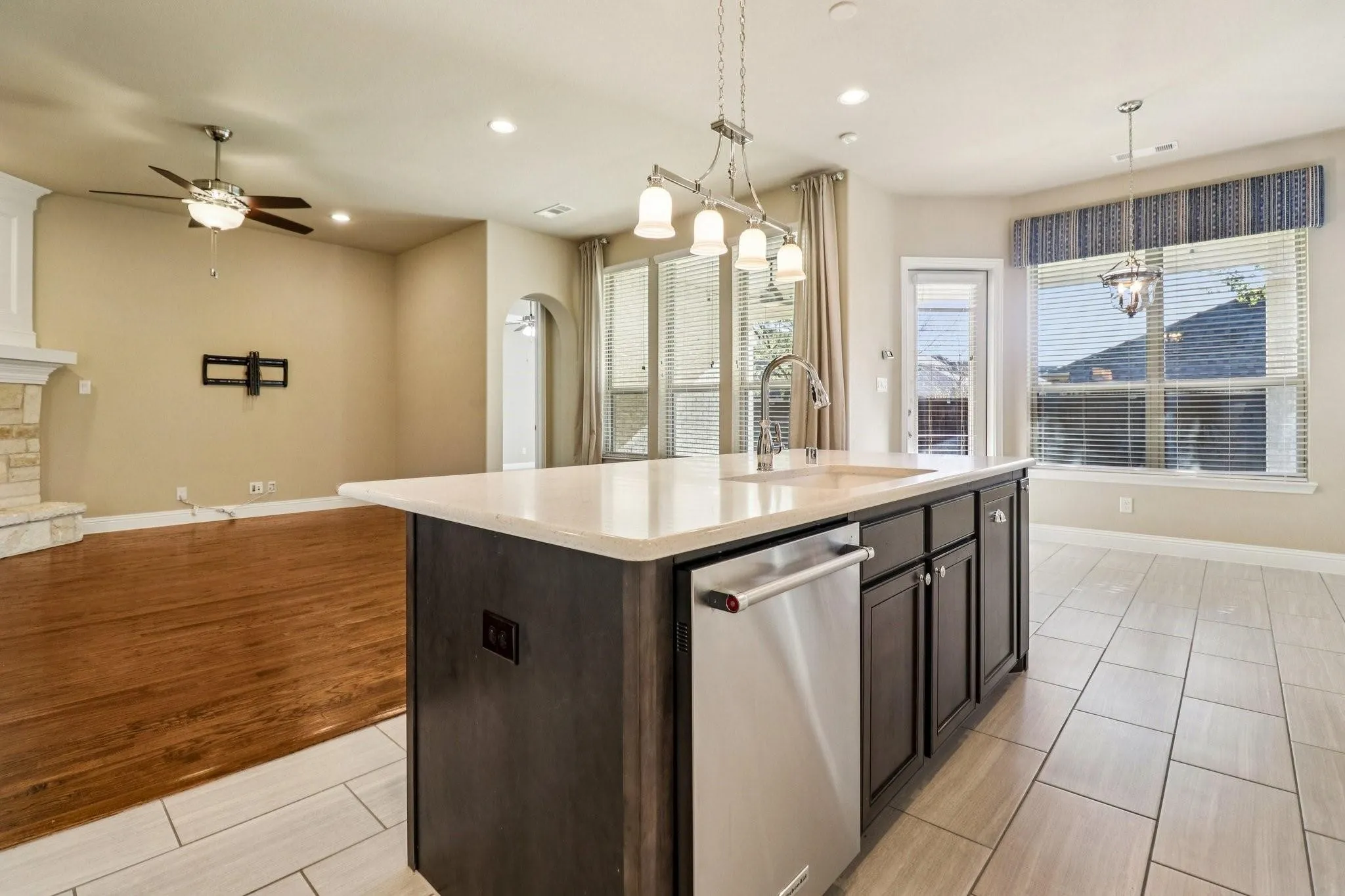 Kitchen island featuring a stainless steel dishwasher, undermount sink with gooseneck faucet, and light-toned countertop