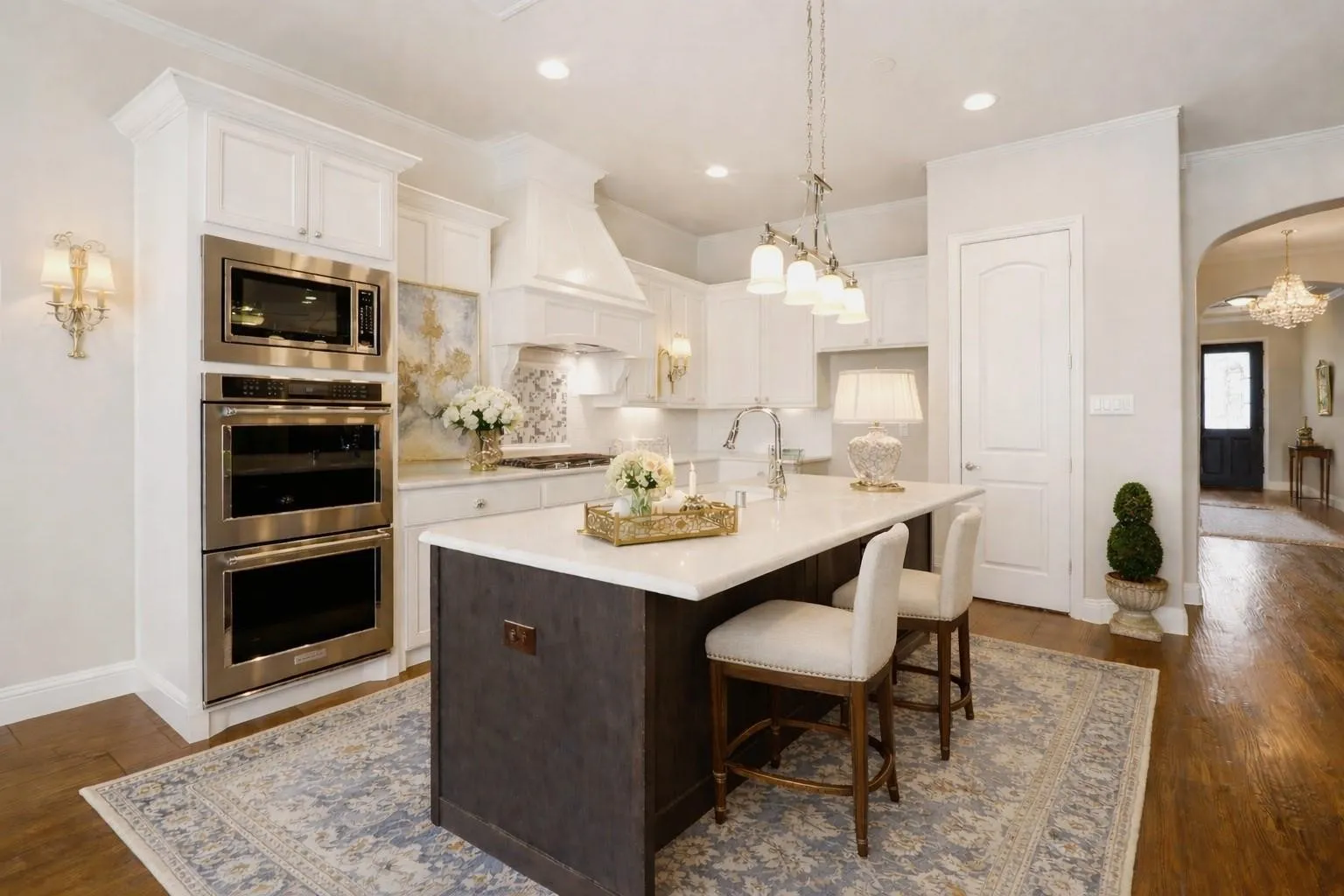 Virtual image. Gourmet kitchen featuring a central island with white countertop, white cabinetry, stainless steel built-in appliances, a tiled backsplash, and wood-finish flooring