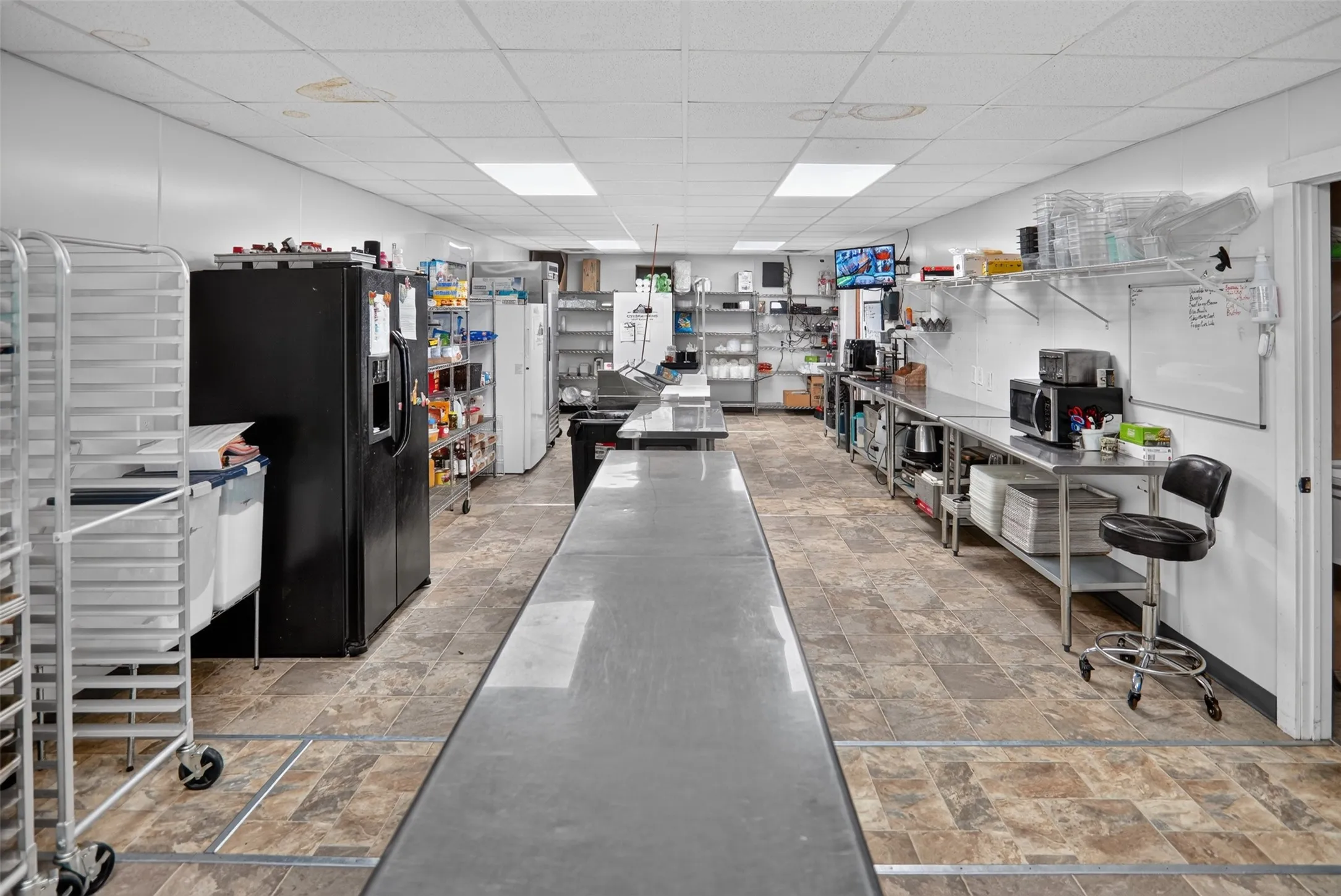 Bright commercial space featuring exposed ceiling trusses, wood-finish flooring, and white paneled walls