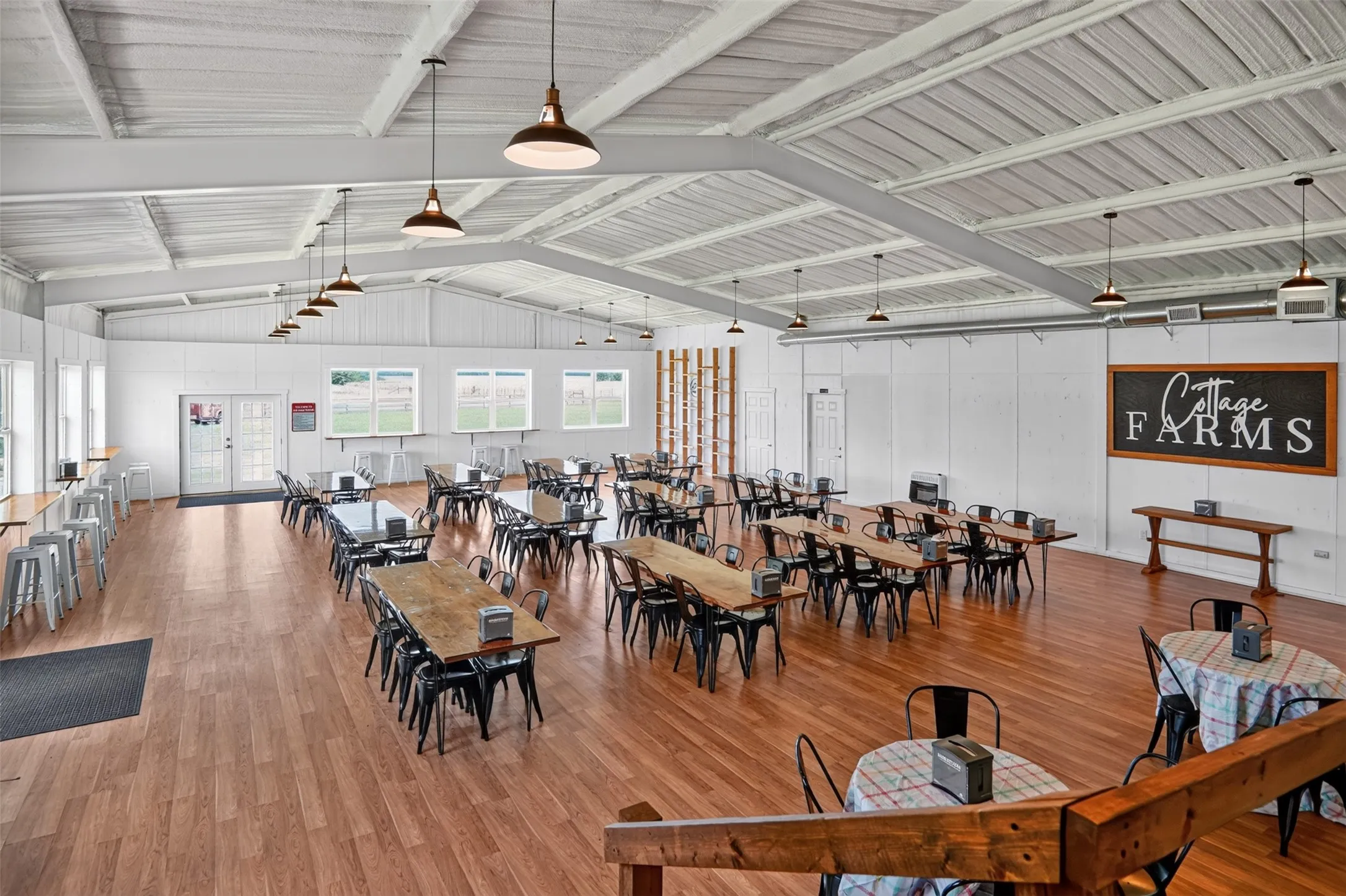 Spacious interior featuring a high vaulted ceiling with exposed white beams and pendant lighting