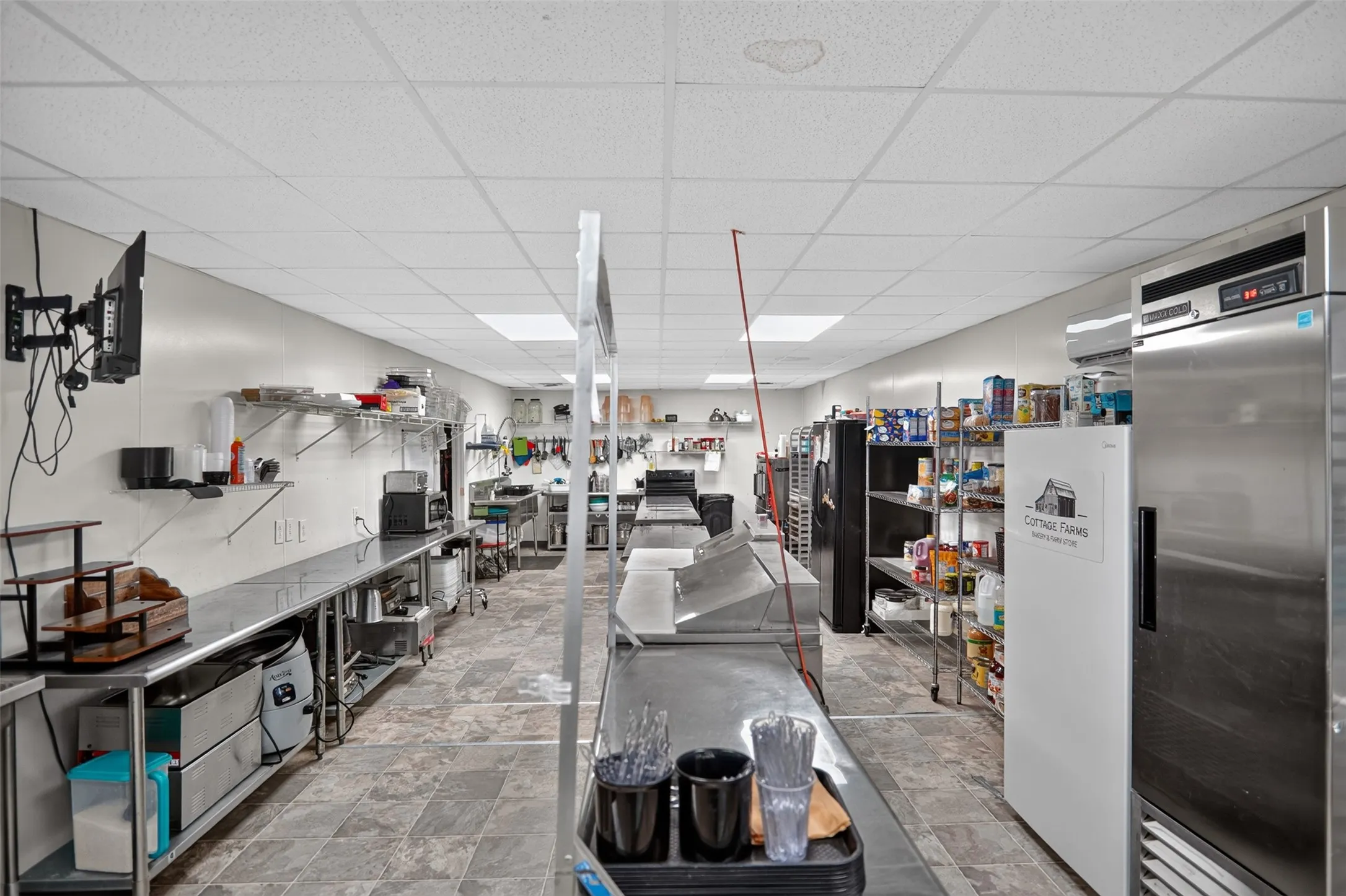 Bright commercial space featuring exposed ceiling trusses, wood-finish flooring, and white paneled walls