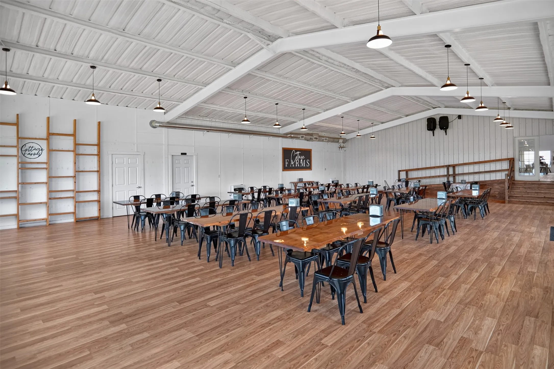 Spacious interior featuring a high vaulted ceiling with exposed white beams and pendant lighting
