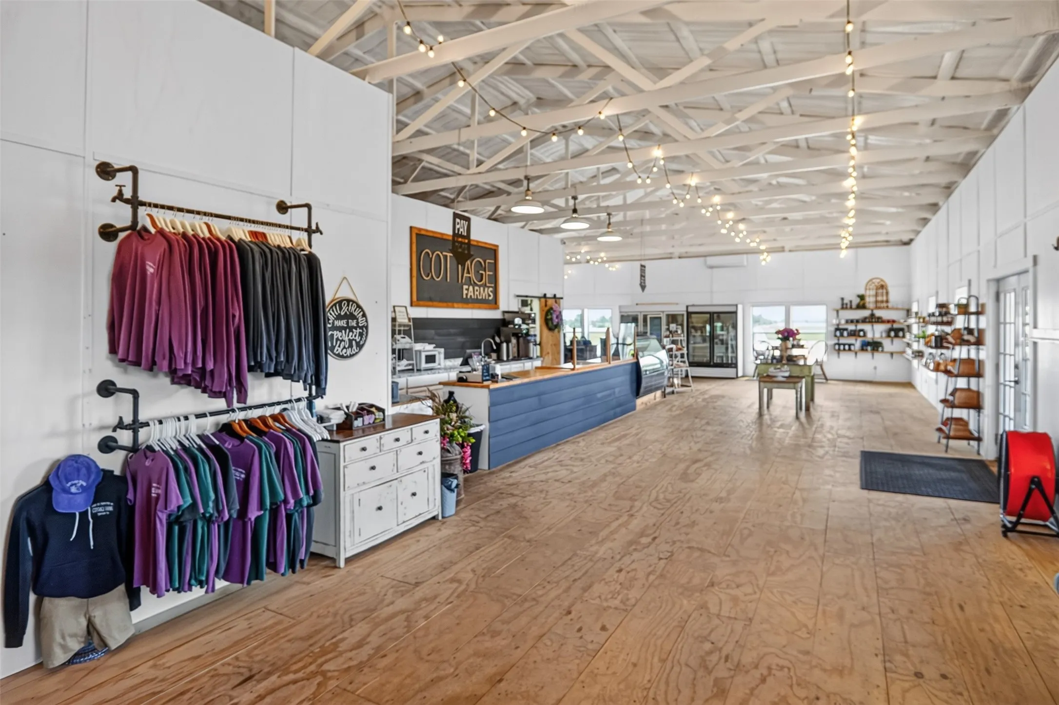 Spacious commercial interior featuring exposed white-painted ceiling trusses and wood-finish flooring