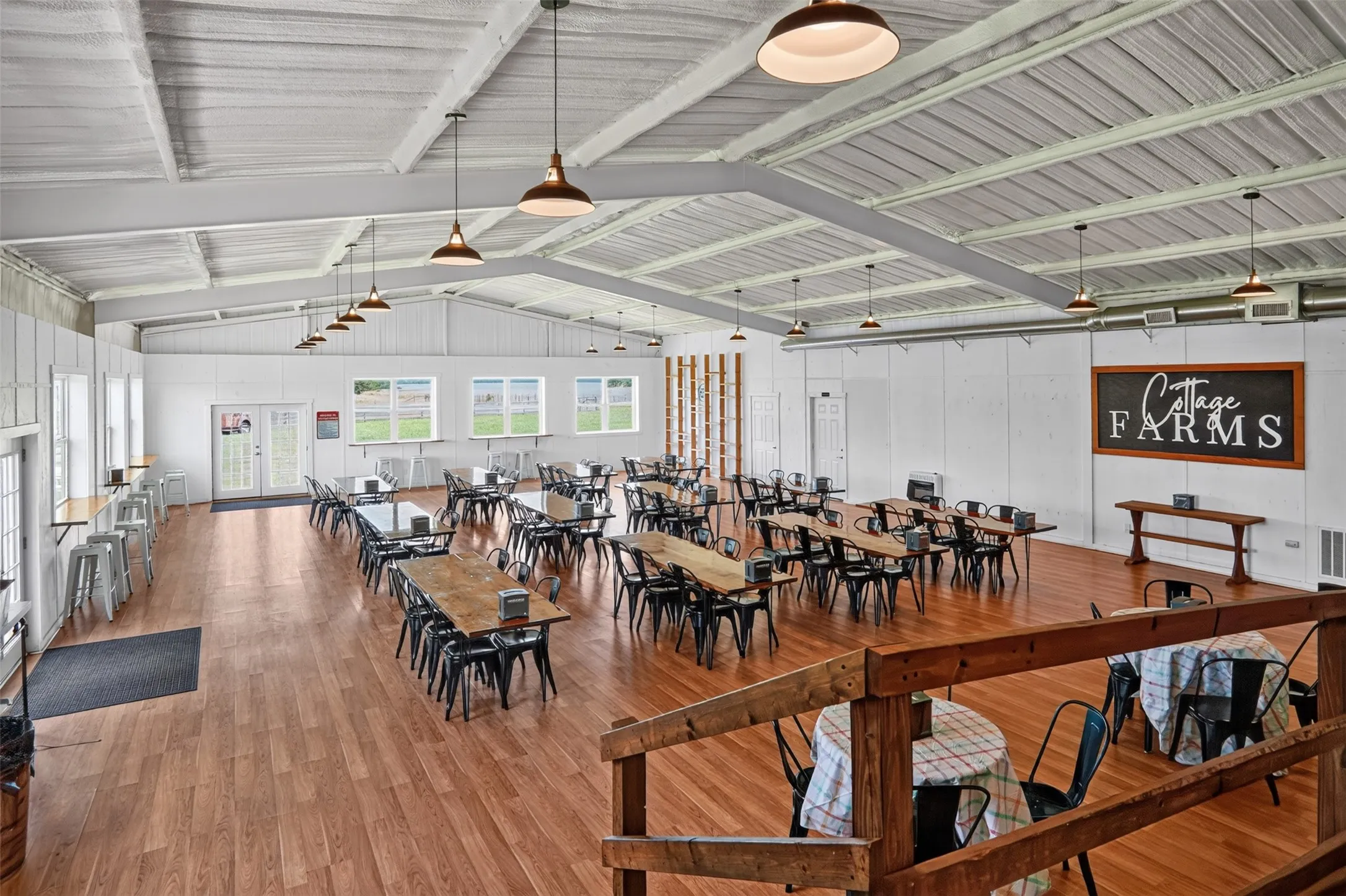 Spacious interior featuring a high vaulted ceiling with exposed white beams and pendant lighting
