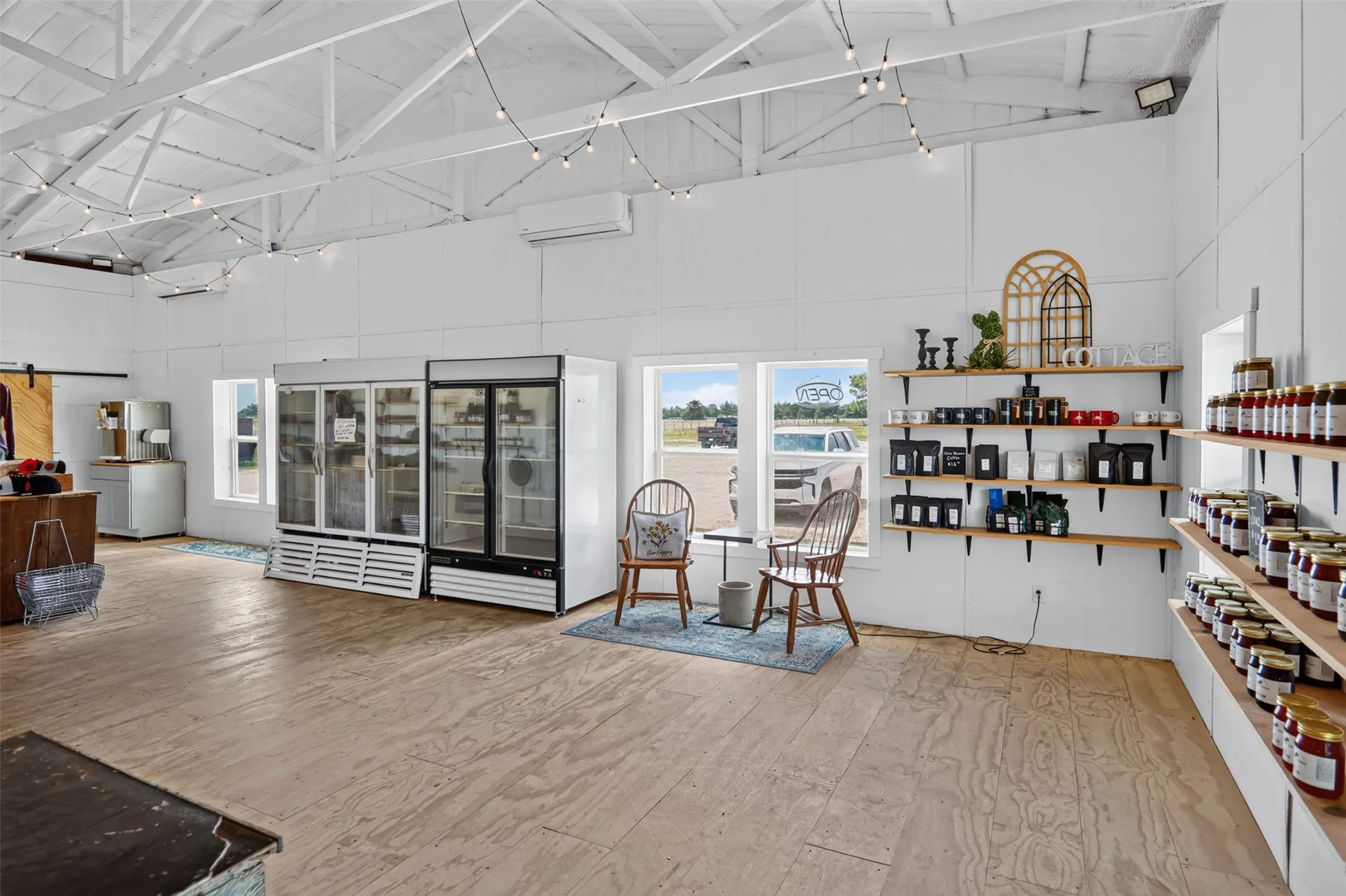 Spacious commercial interior featuring exposed white-painted ceiling trusses and wood-finish flooring