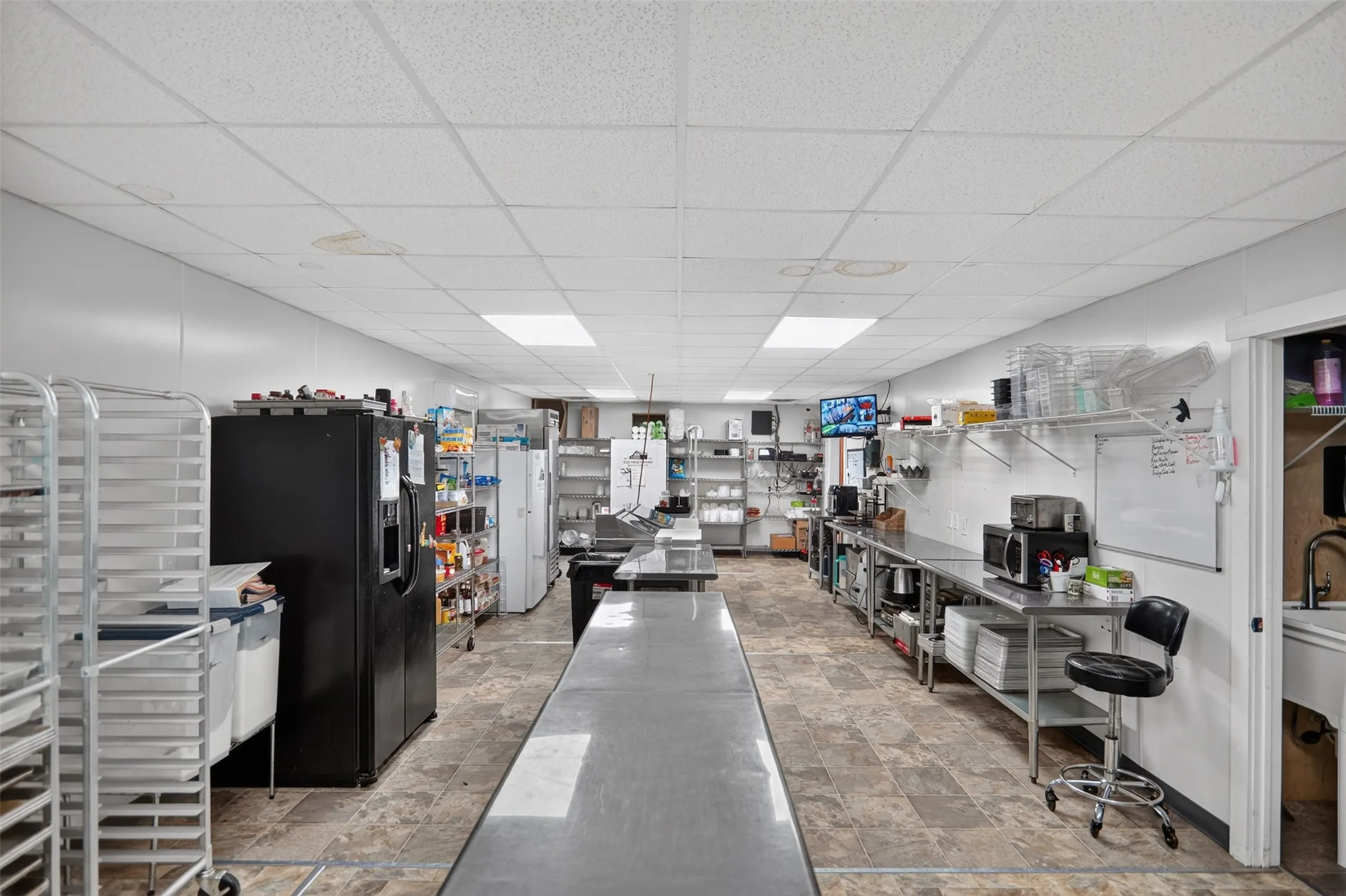 Bright commercial space featuring exposed ceiling trusses, wood-finish flooring, and white paneled walls