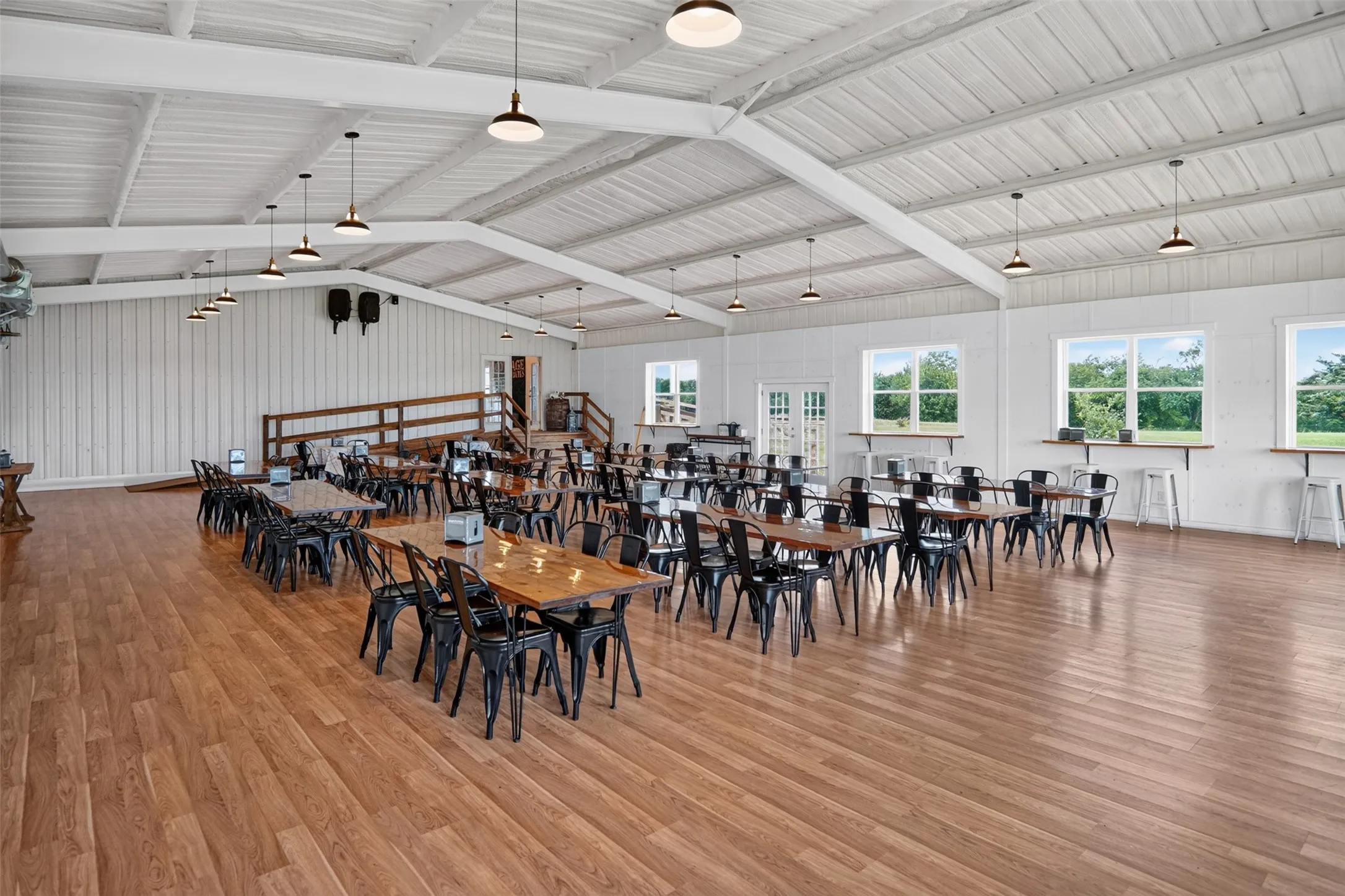 Spacious interior featuring a high vaulted ceiling with exposed white beams and pendant lighting