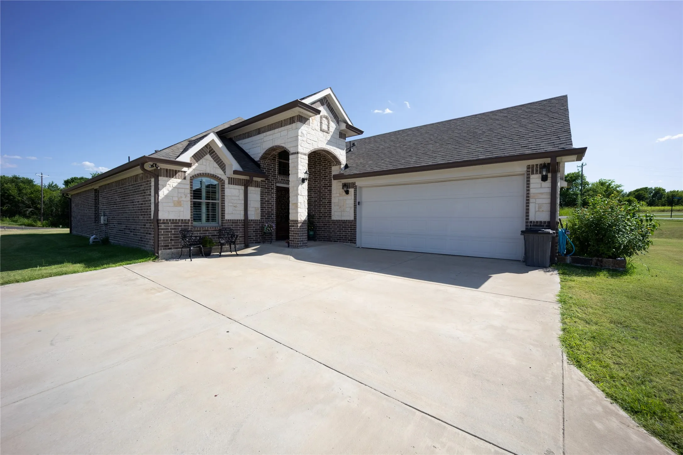 Brick and stone exterior featuring an arched entryway, gabled rooflines, and a two-car garage