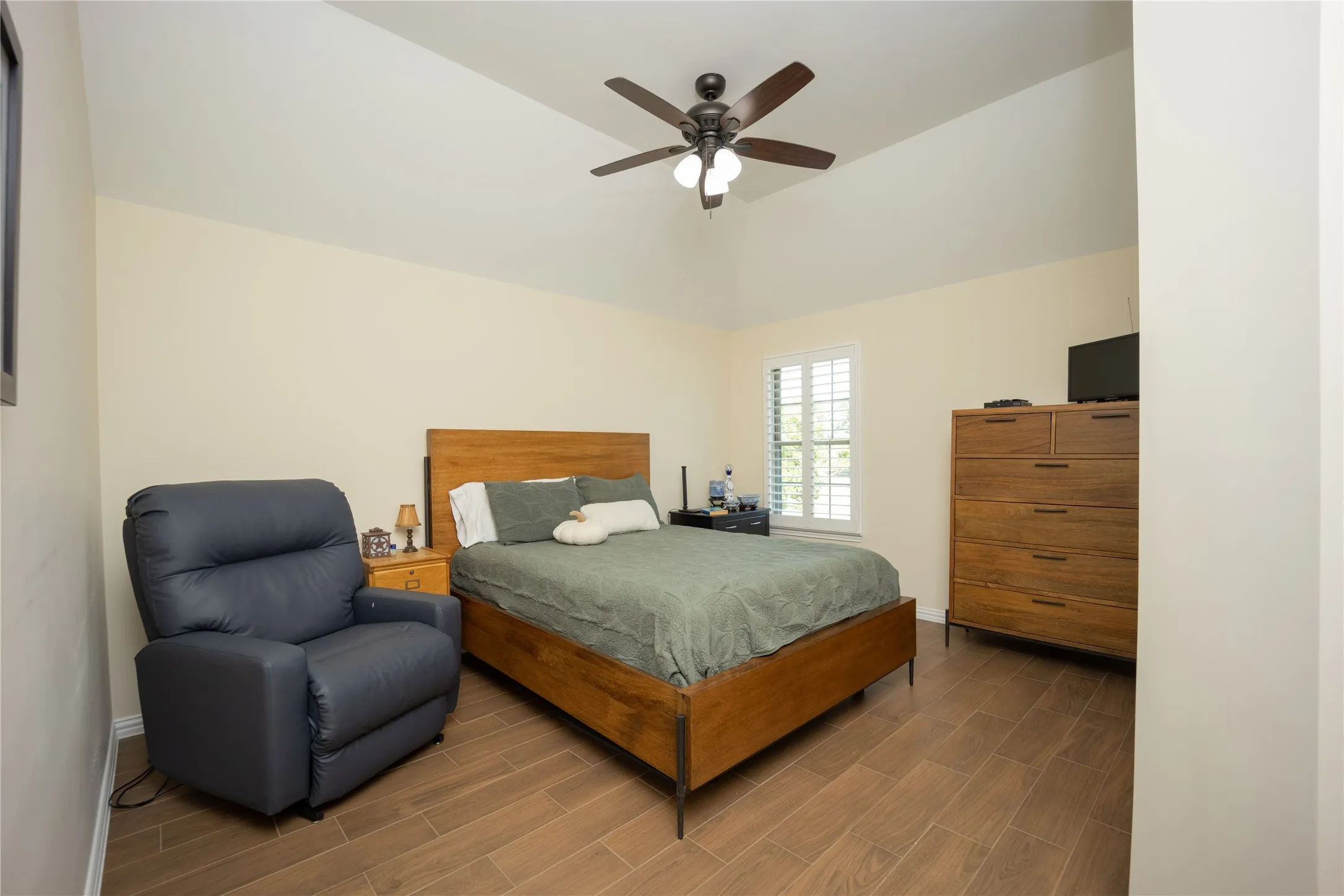 Interior room featuring wood-finish flooring, vaulted ceiling, and a ceiling fan with integrated lighting