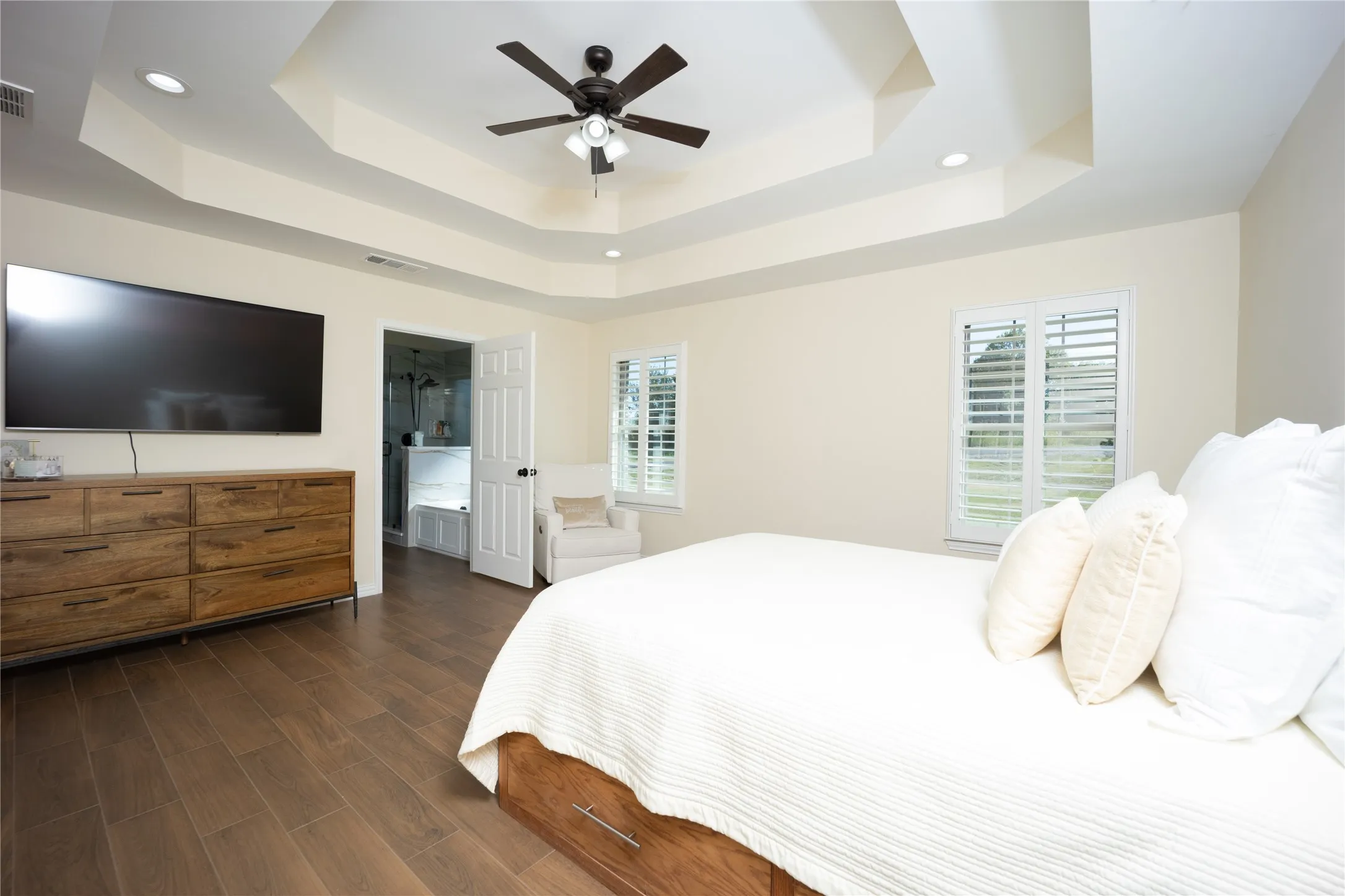 Spacious room featuring a tiered tray ceiling with recessed lighting and a ceiling fan
