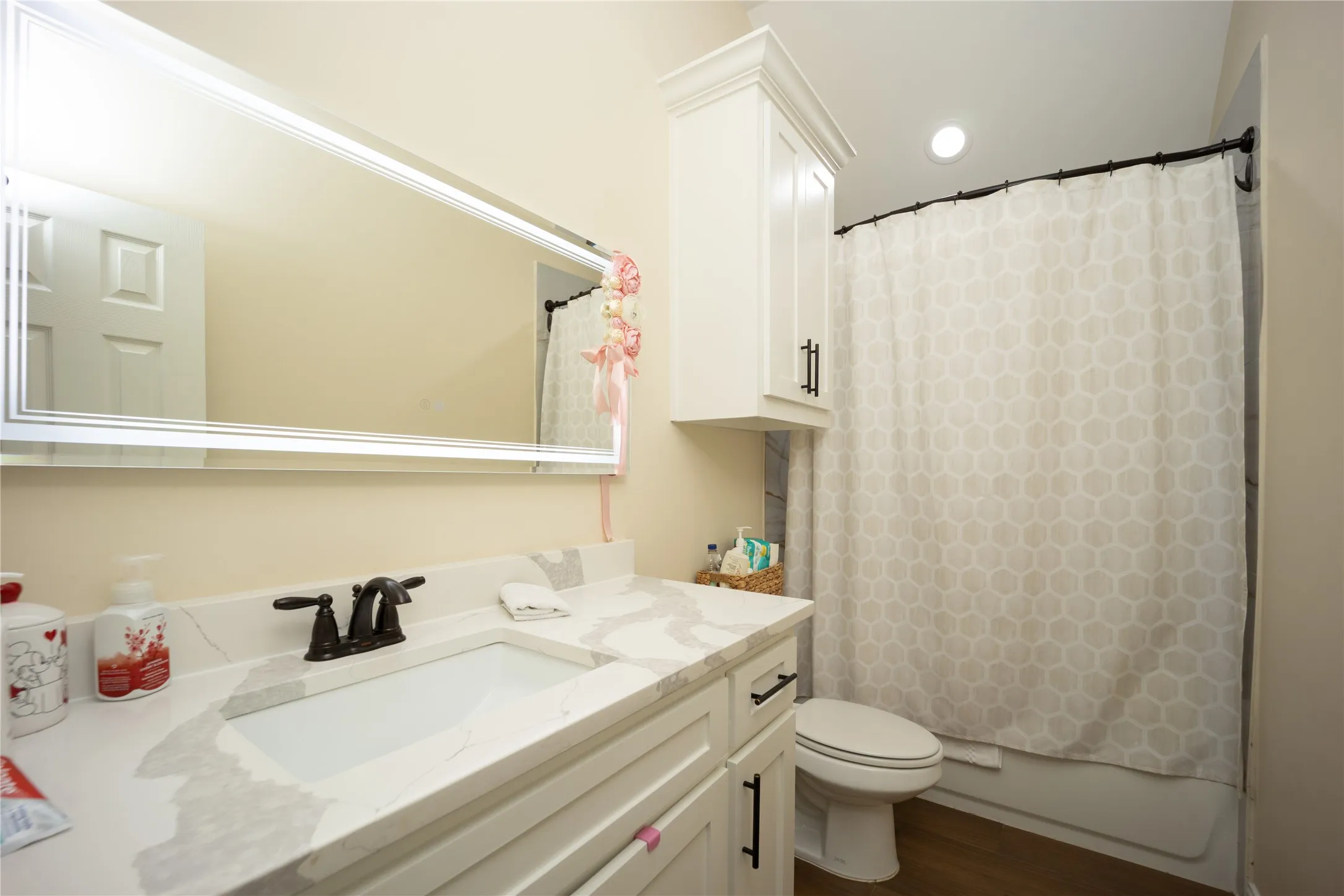 Bathroom featuring a white vanity with an integrated sink, a faux marble countertop, and dark bronze hardware