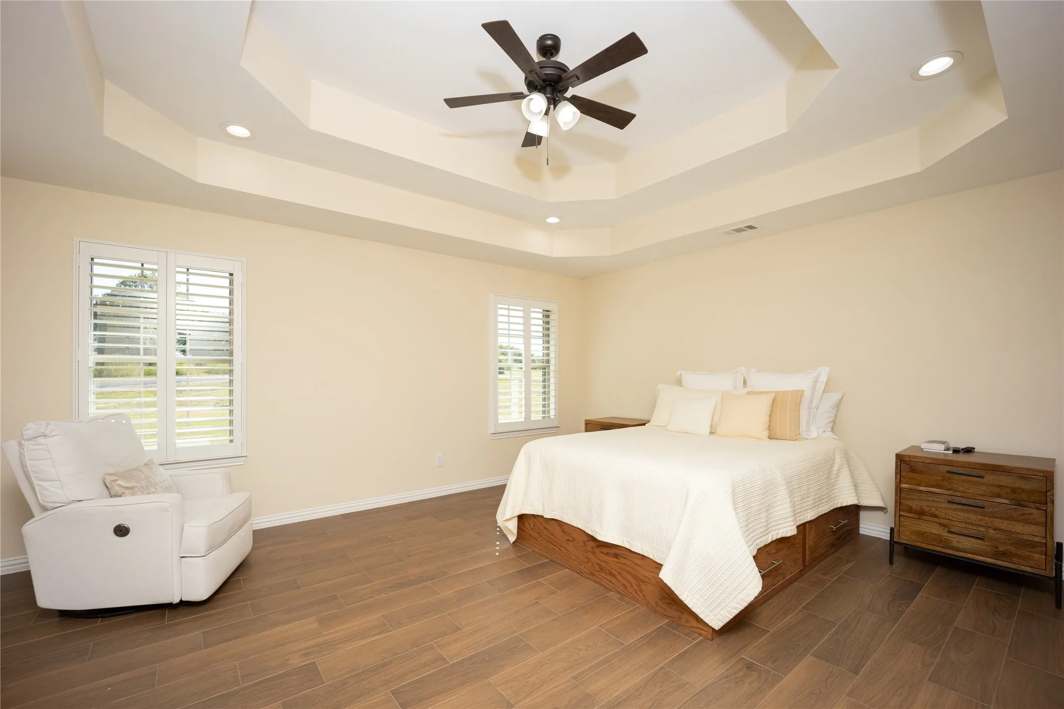 Spacious room featuring a tiered tray ceiling with recessed lighting and a ceiling fan