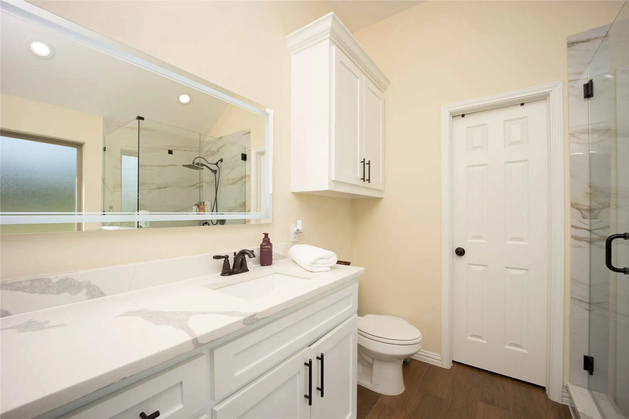 Bathroom featuring a white vanity with a light-toned countertop, a frameless mirror, and a glass-enclosed shower with a rainfall showerhead