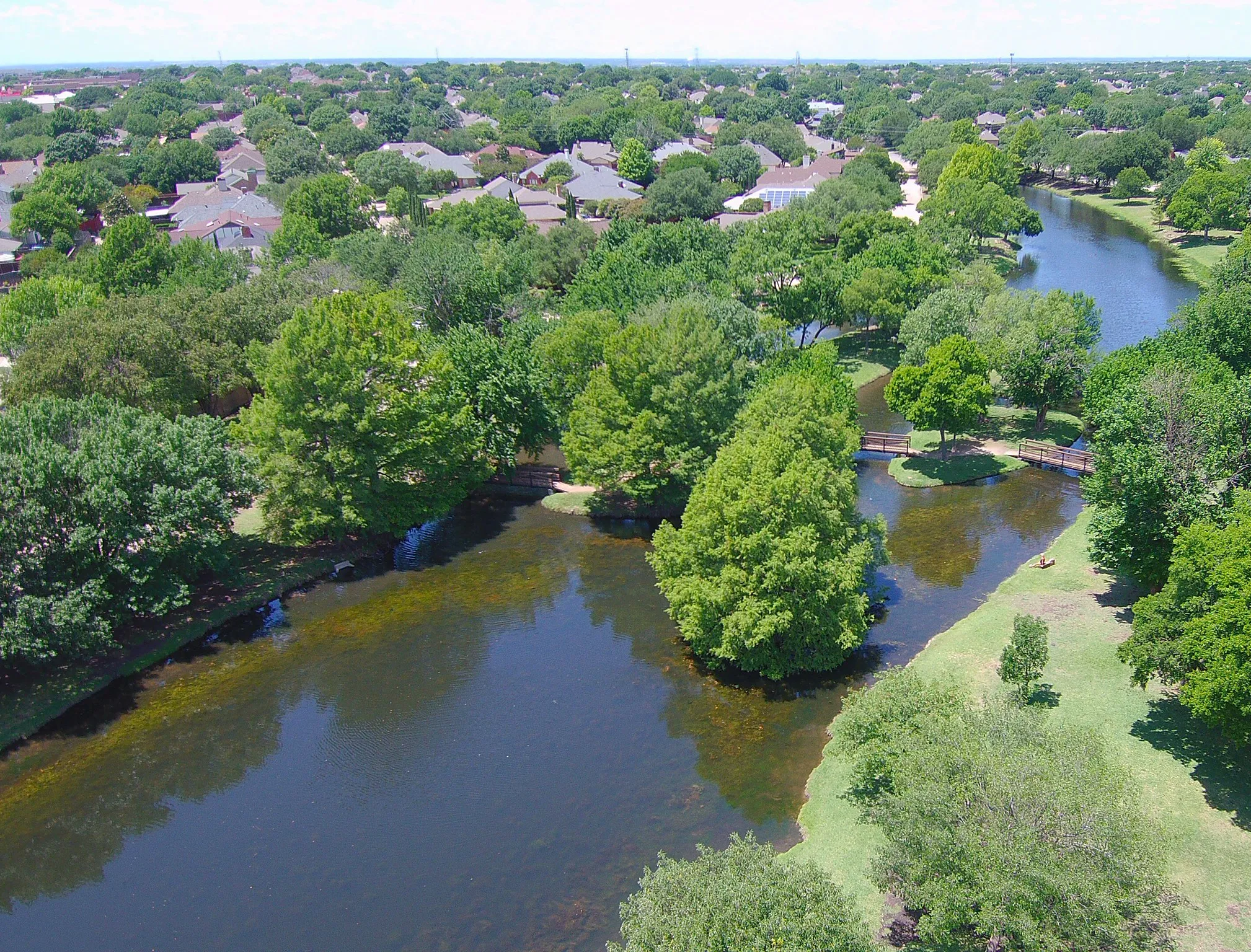 Aerial perspective showcasing a residential area with extensive tree canopy and a winding waterway