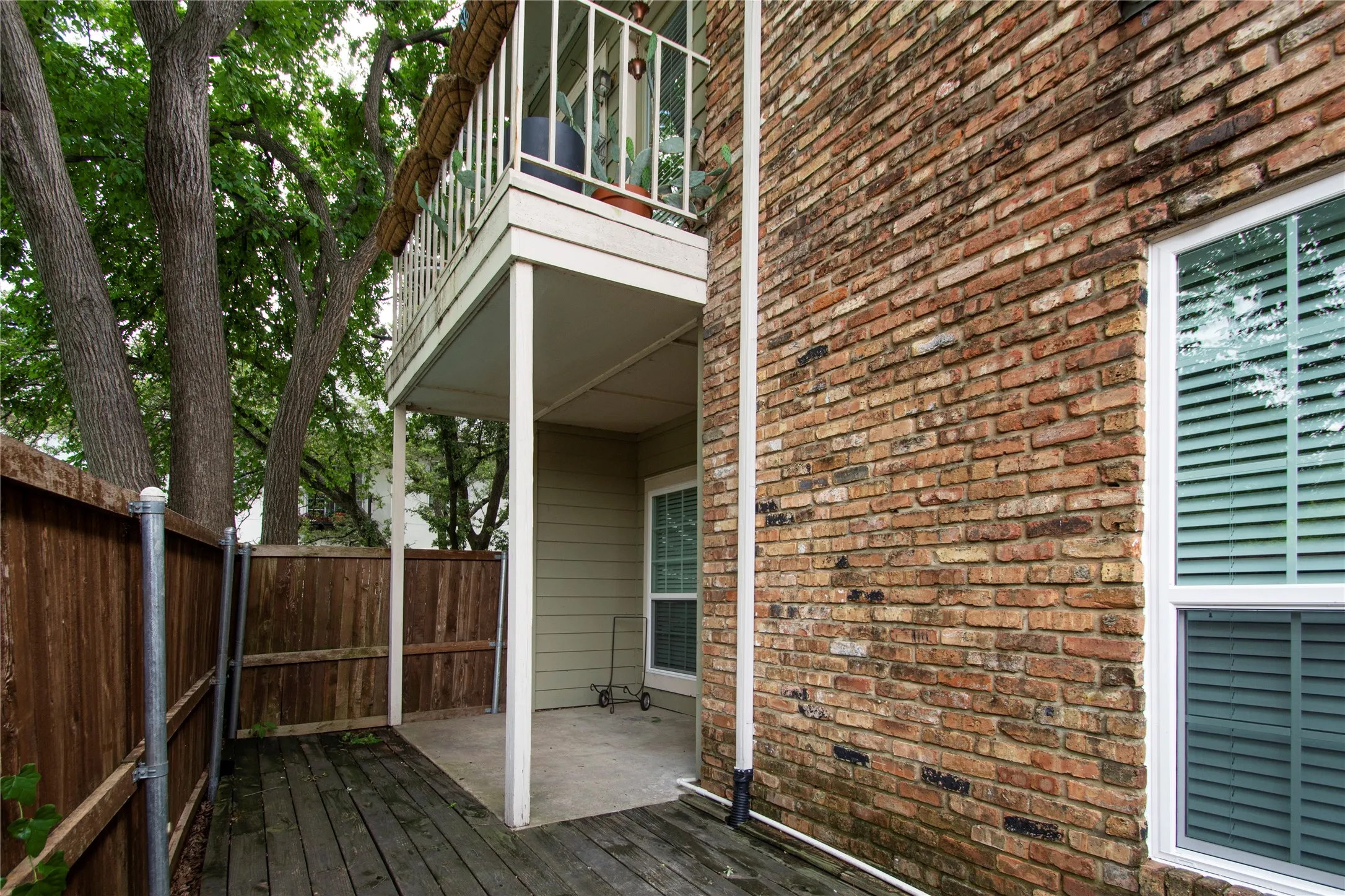 Exterior brick facade with white-framed windows featuring horizontal blinds