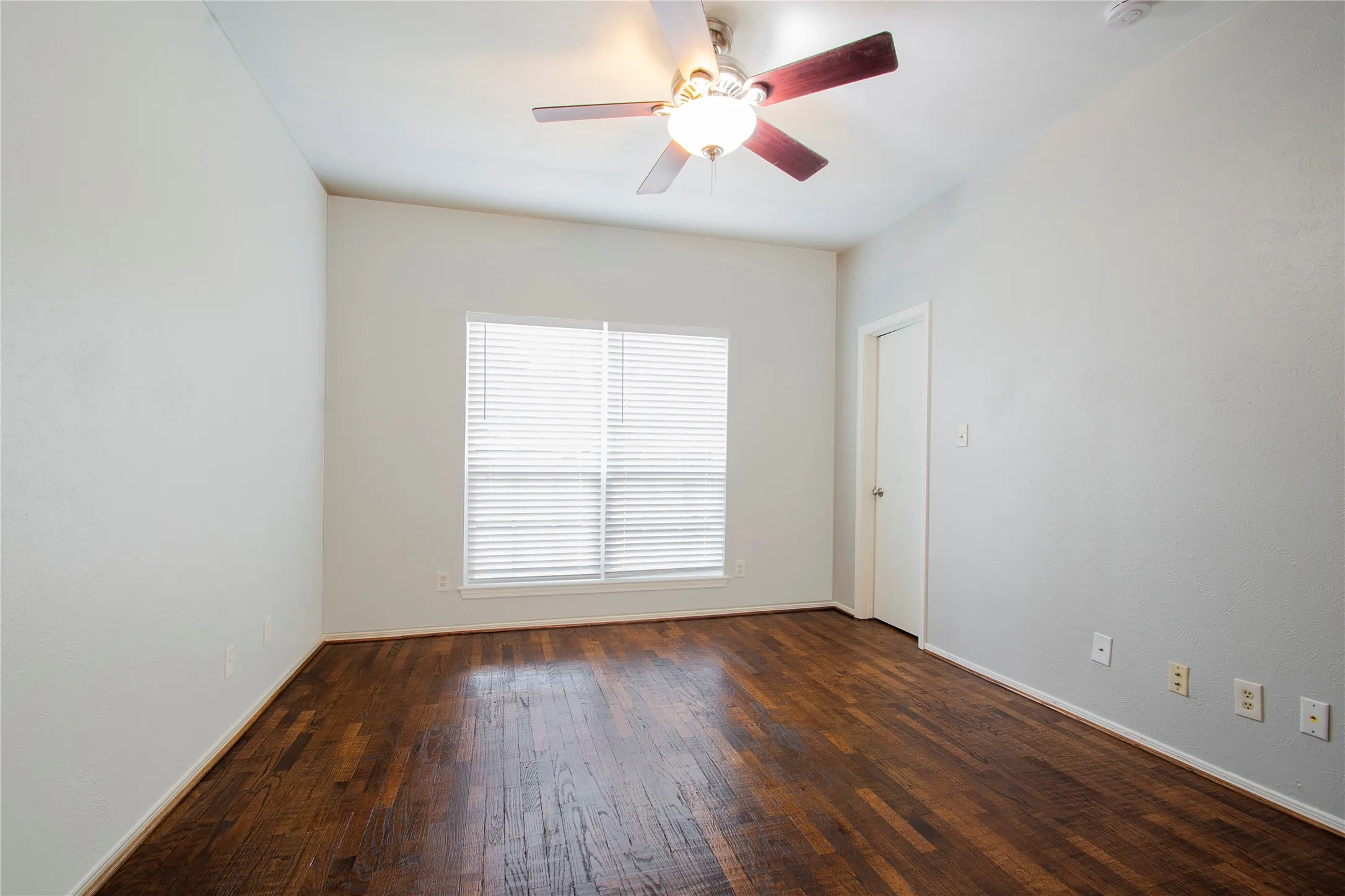 Room featuring wood-finish flooring, a vaulted ceiling, and a ceiling fan with light fixture