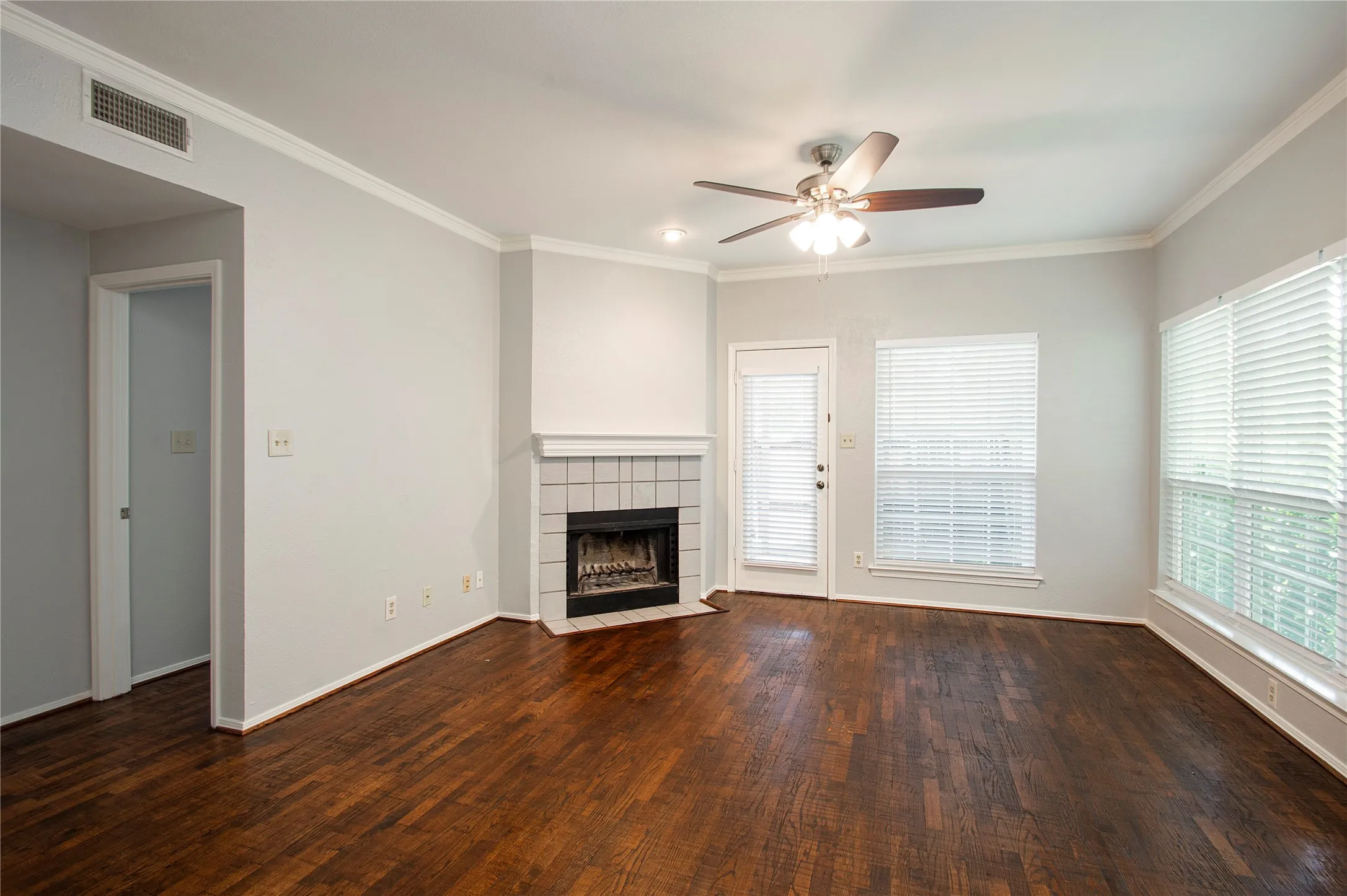 Living space featuring wood-finish flooring and a corner fireplace with a tiled surround