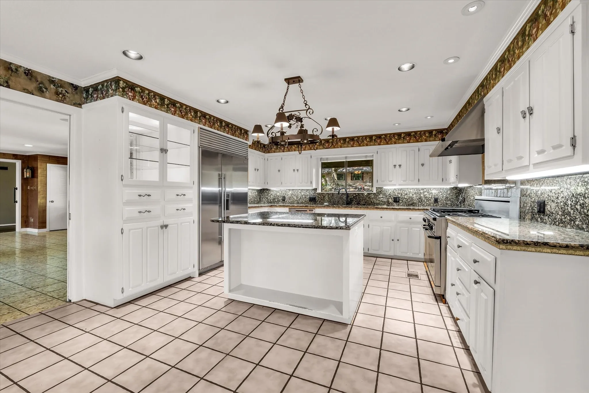 Spacious kitchen featuring white cabinetry, granite countertops, tile flooring, and stainless steel appliances