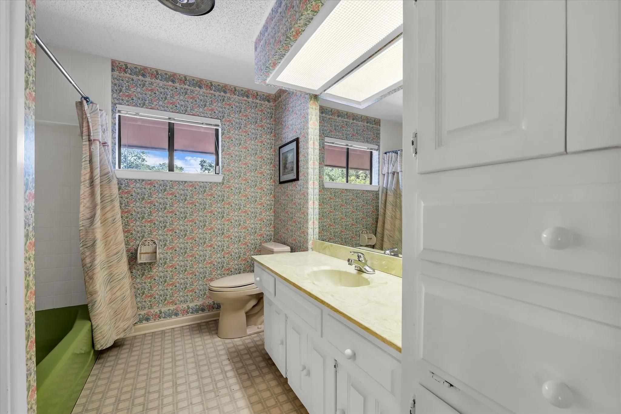 Bathroom featuring a single vanity with a light-toned countertop, a built-in mirror, and white cabinetry