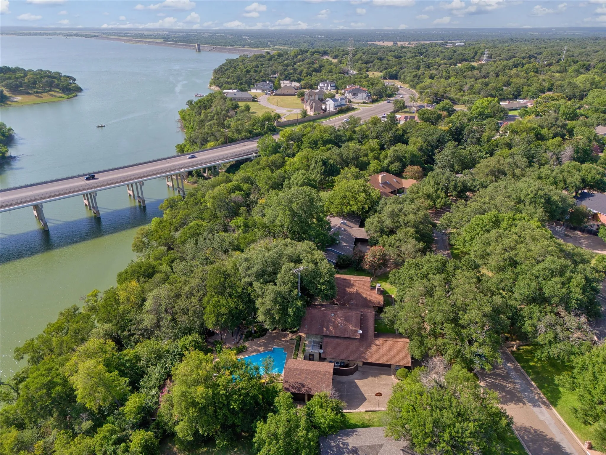 Aerial perspective showcasing a residential property with a private swimming pool, surrounded by mature trees