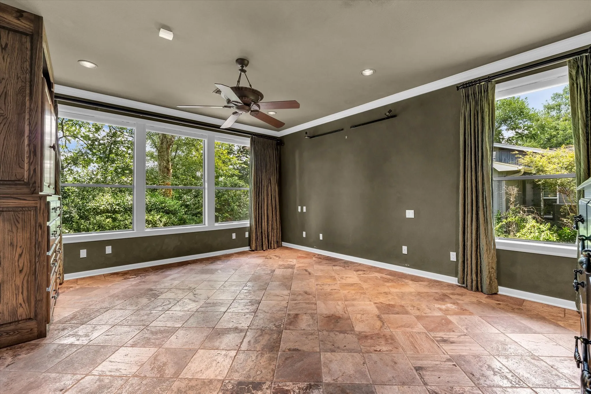 Spacious room featuring large windows, wood-finish flooring, a ceiling fan, recessed lighting, and built-in cabinetry