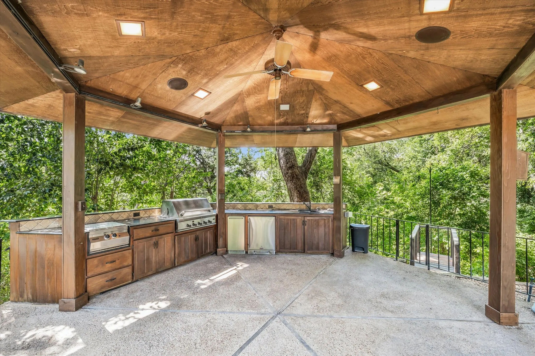 Expansive outdoor living area featuring a vaulted wood-finish ceiling with recessed lighting and ceiling fan