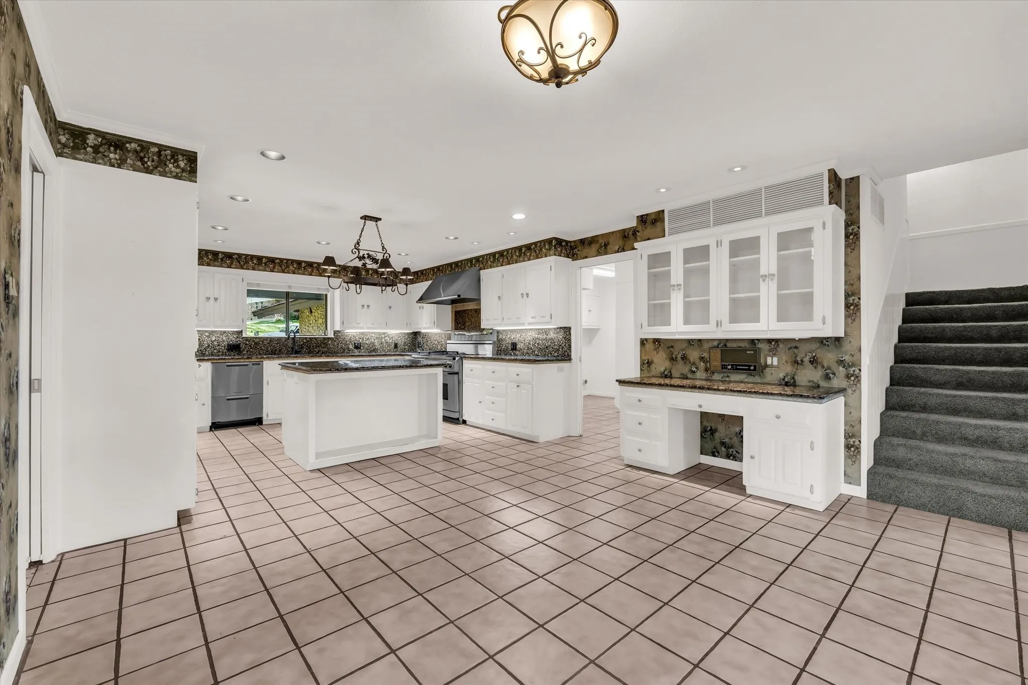 Spacious kitchen featuring white cabinetry, a central island, and stone countertops