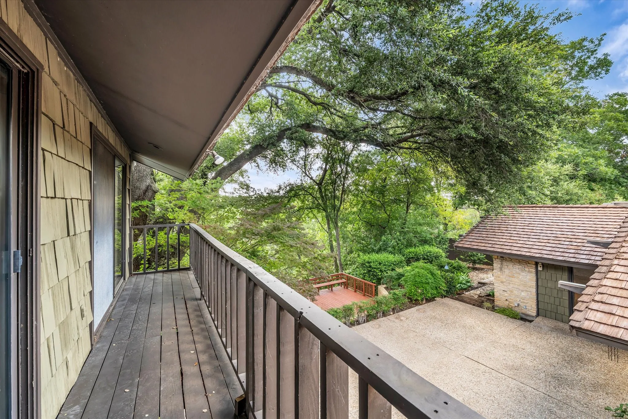 Elevated wood-plank balcony with a wood railing and shake siding