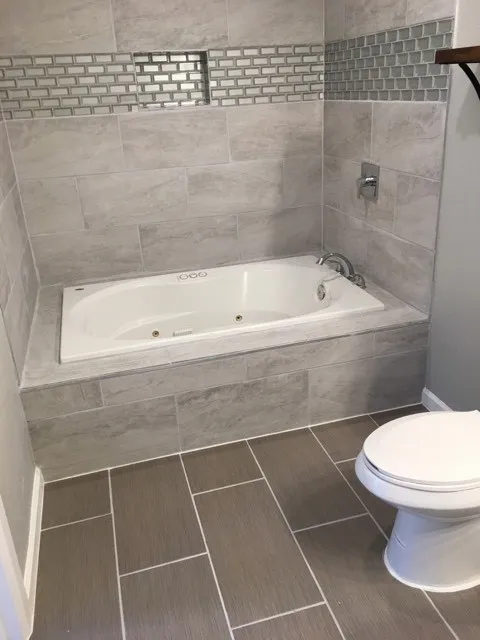 Bathroom featuring tile flooring, tiled bath, and toilet