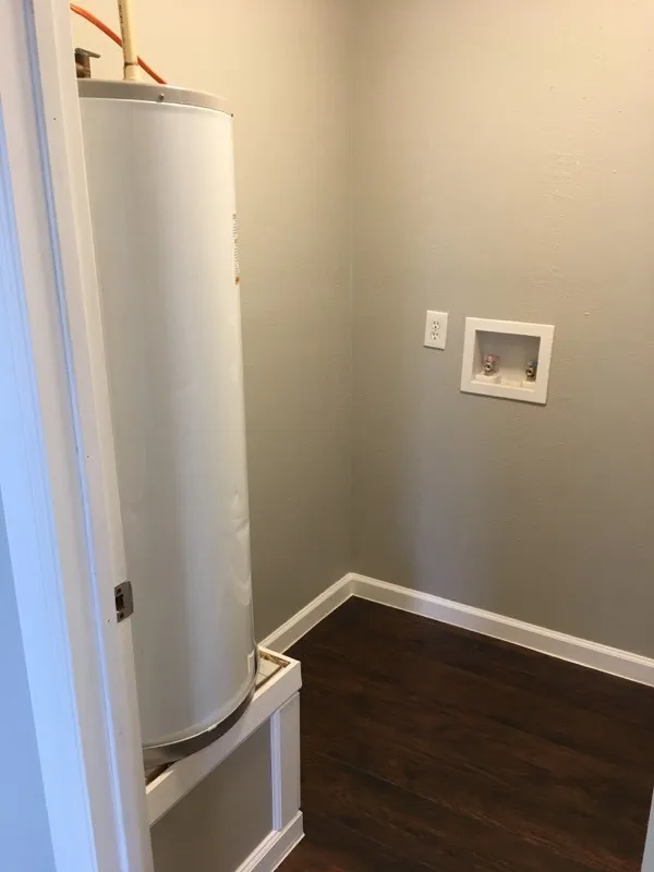 Laundry area featuring dark hardwood / wood-style flooring, washer hookup, and water heater