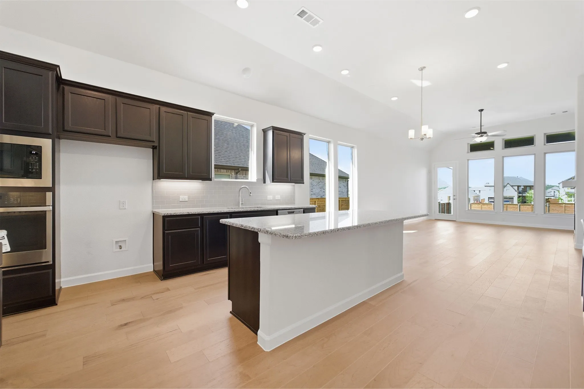 Open-concept kitchen and living area featuring wood-finish flooring, recessed lighting, and a kitchen island with a stone countertop
