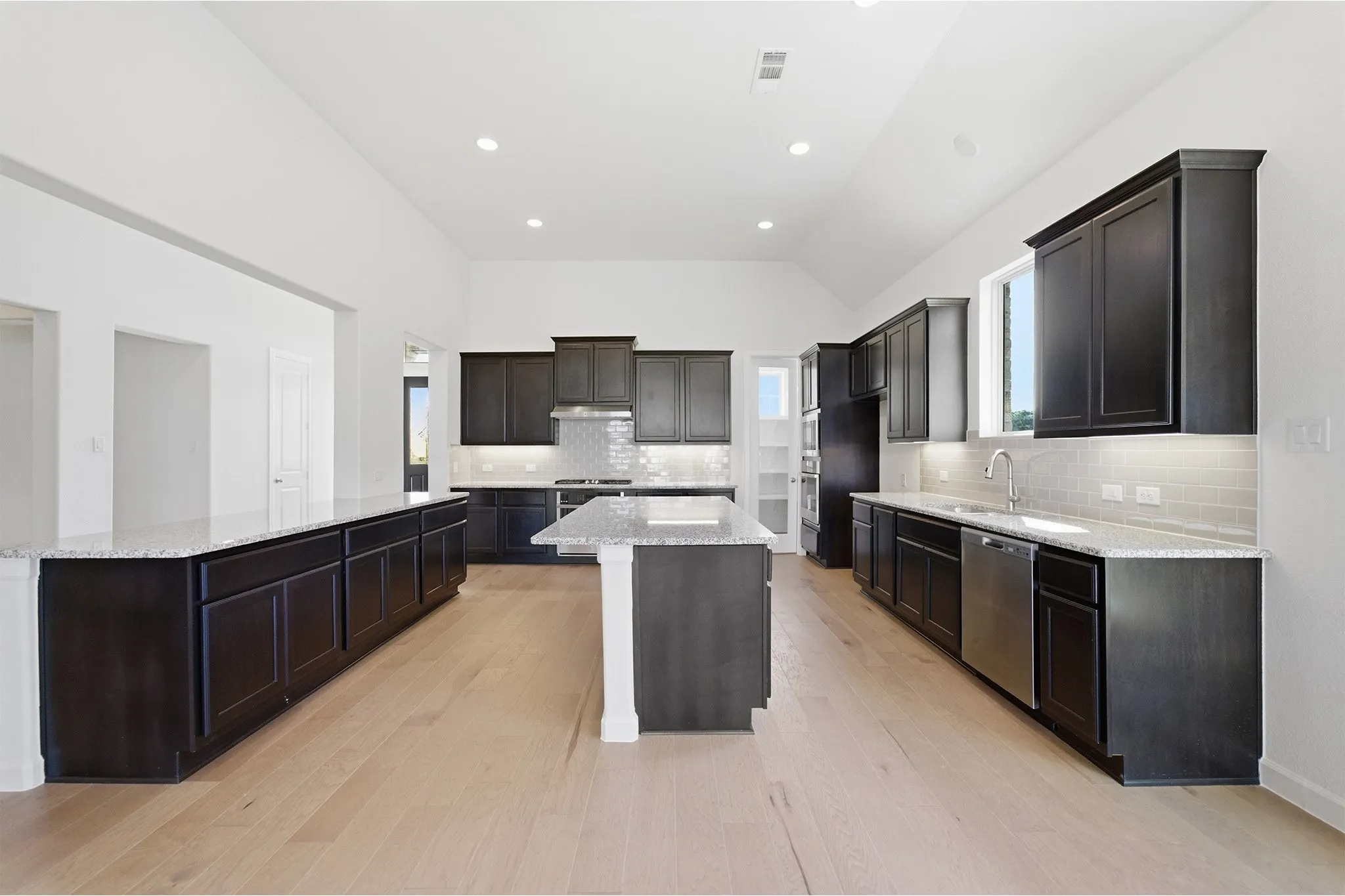 Spacious kitchen featuring dark wood cabinetry, light-toned wood-finish flooring, and white countertops