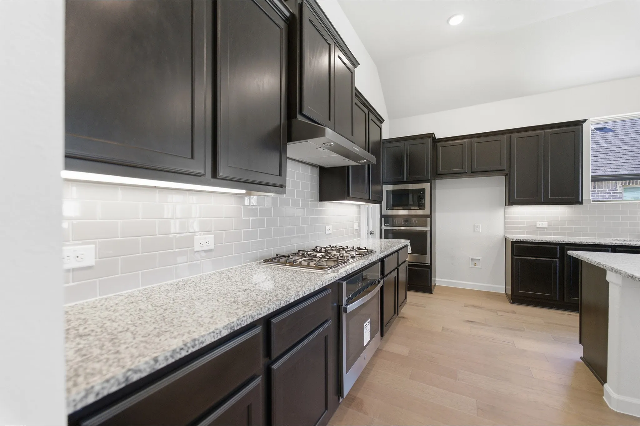Kitchen featuring dark cabinetry, speckled countertops, and a subway tile backsplash