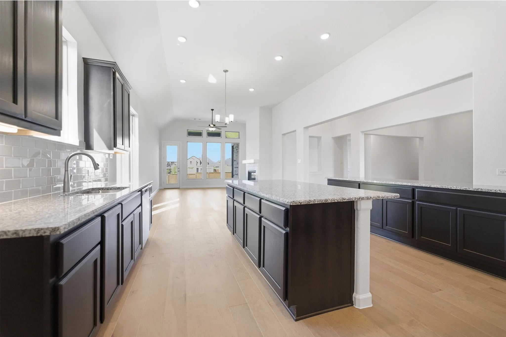 Contemporary kitchen featuring an expansive center island, dark cabinetry, and light speckled countertops