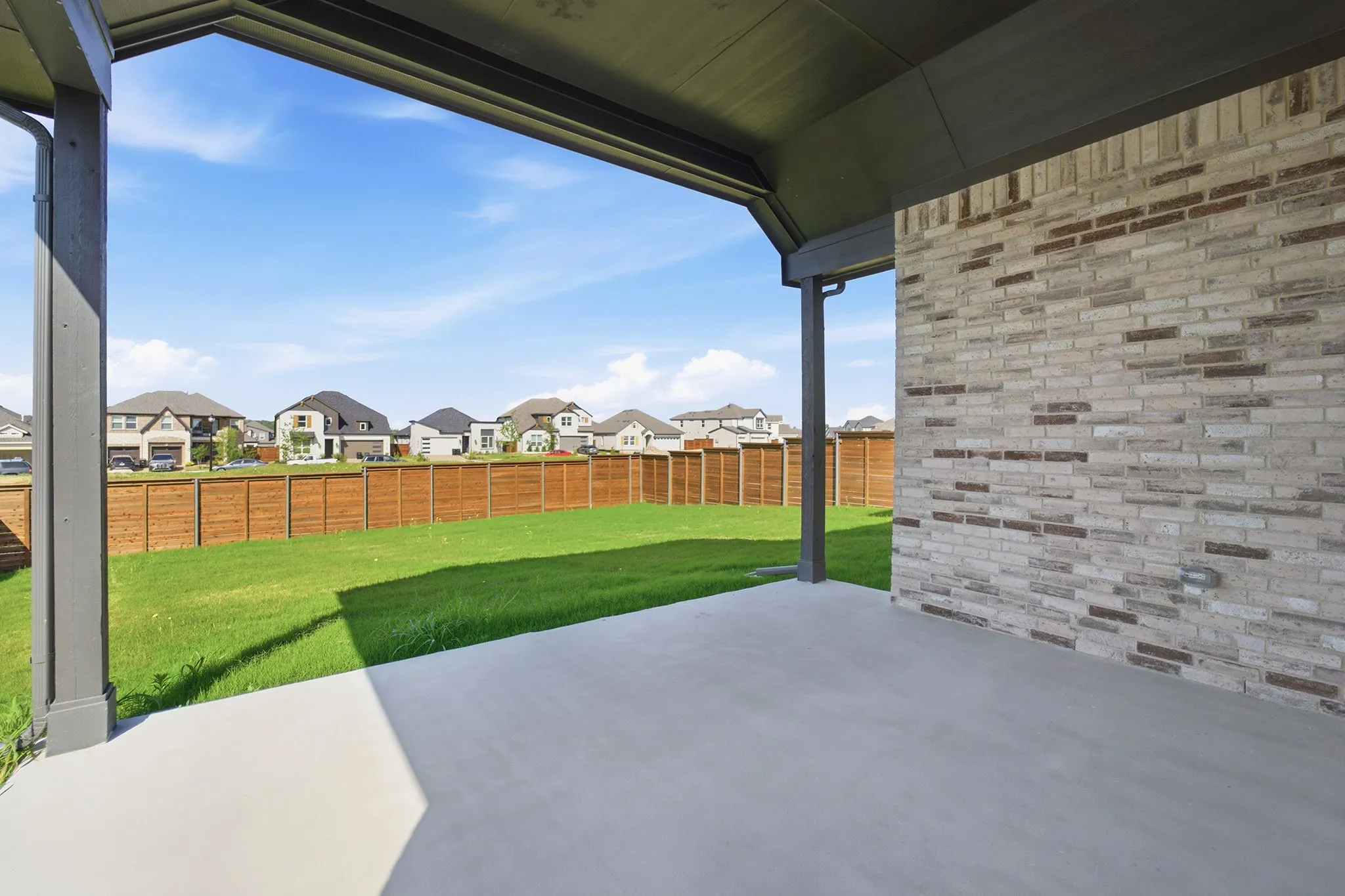 Covered patio with a concrete surface, featuring a variegated light brick exterior wall
