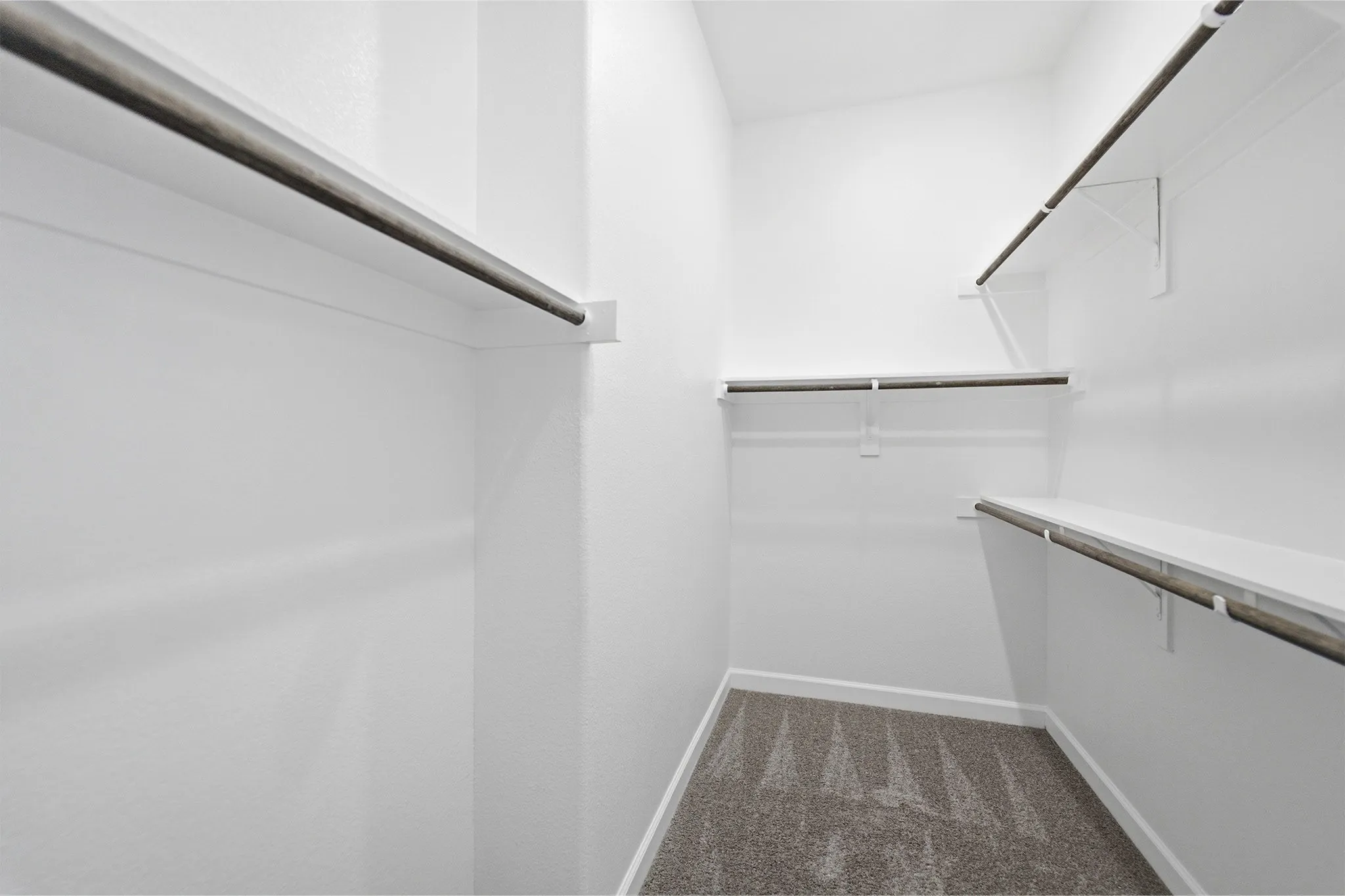 Walk-in closet featuring multiple shelving units and hanging rods
