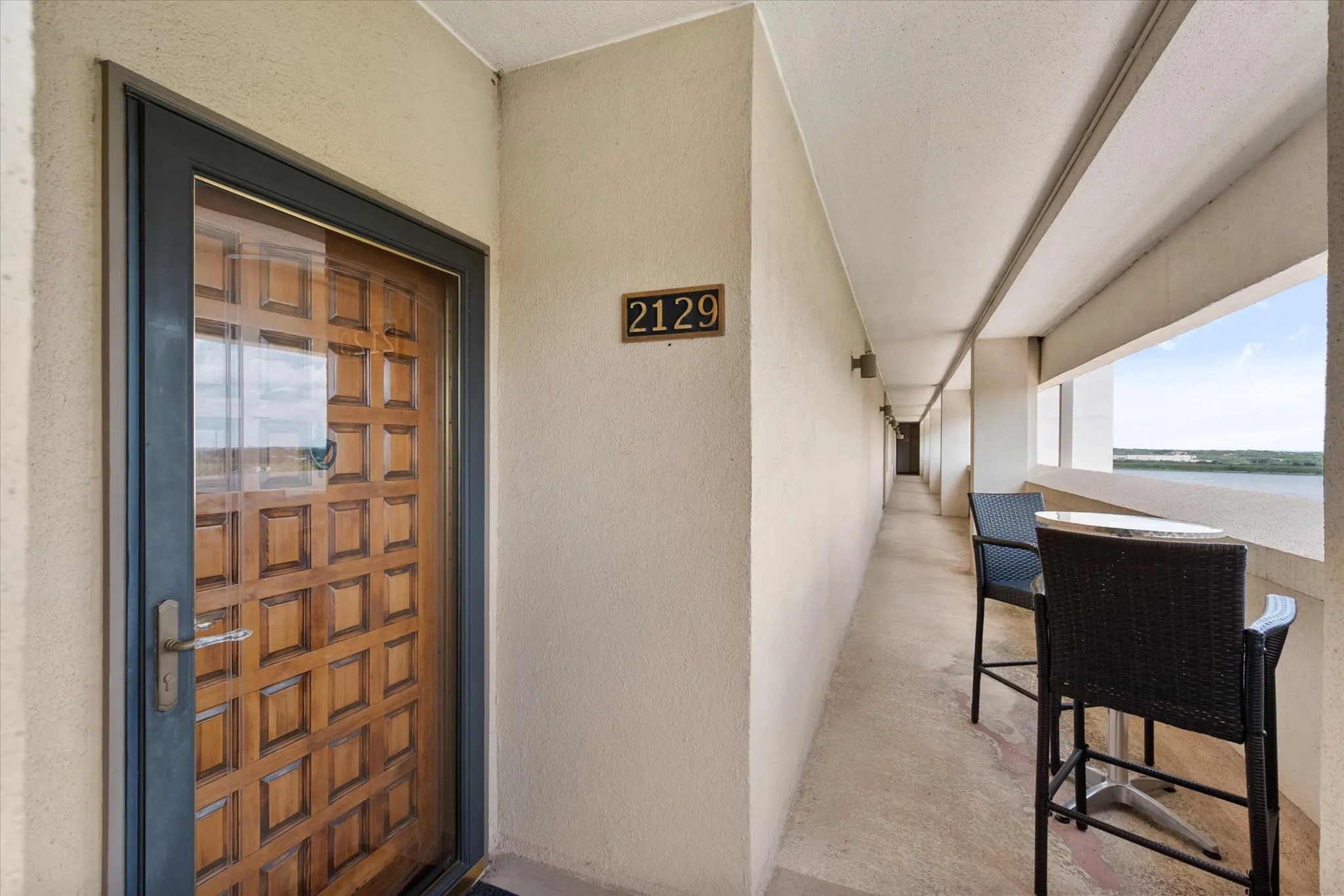 Beautiful, solid wood entry door to the unit and an additional covered, open air sitting area in the corridor.