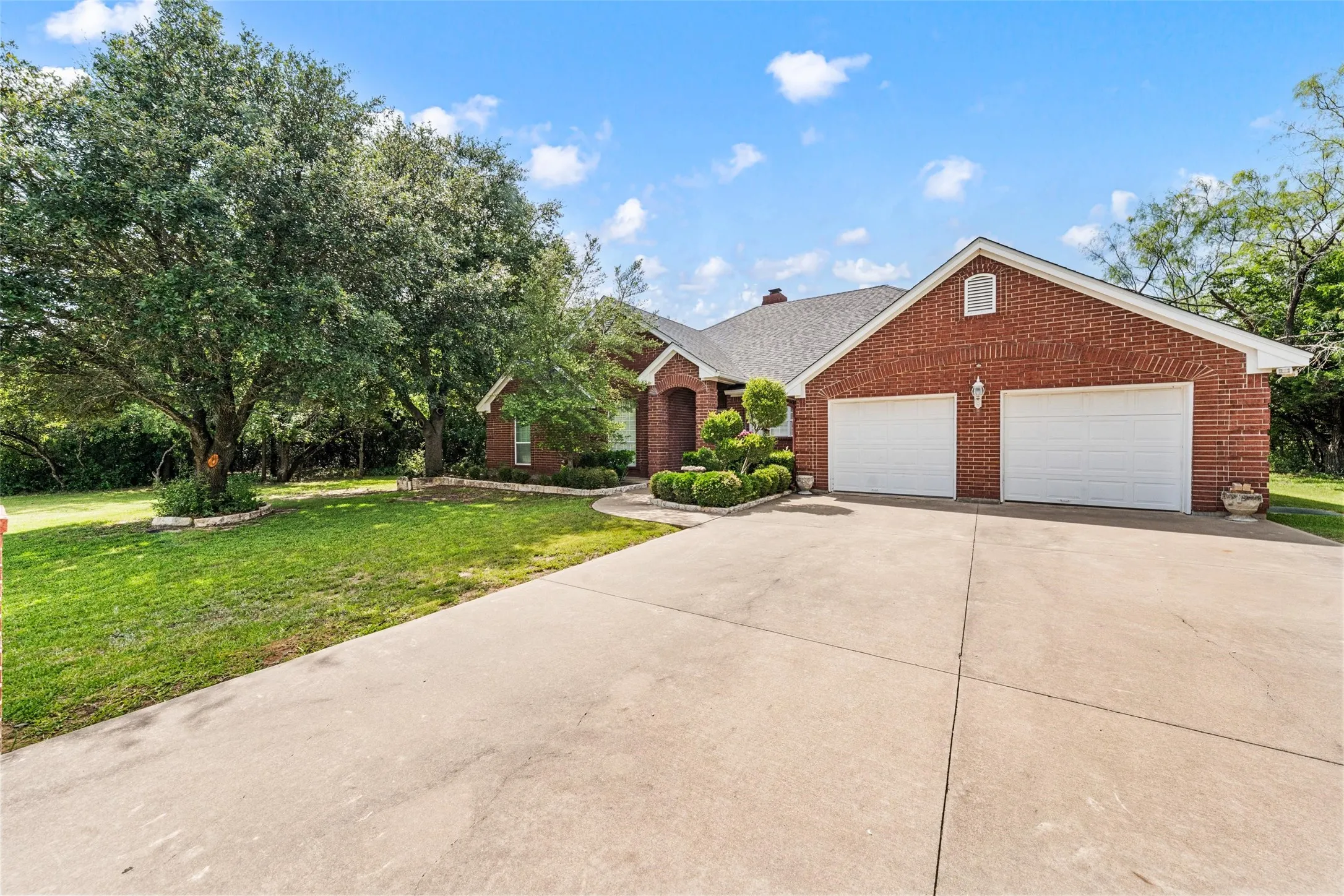 Brick exterior with a shingle roof and a concrete driveway